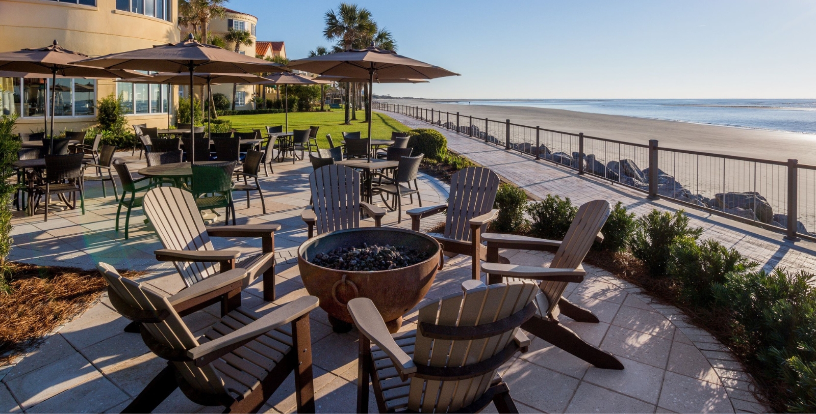 a patio with chairs and umbrellas and a beach
