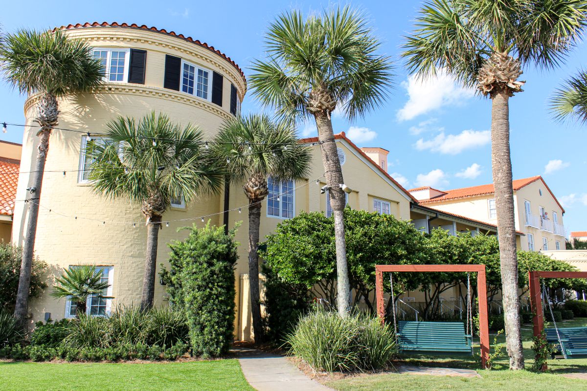 a building with palm trees and a swing