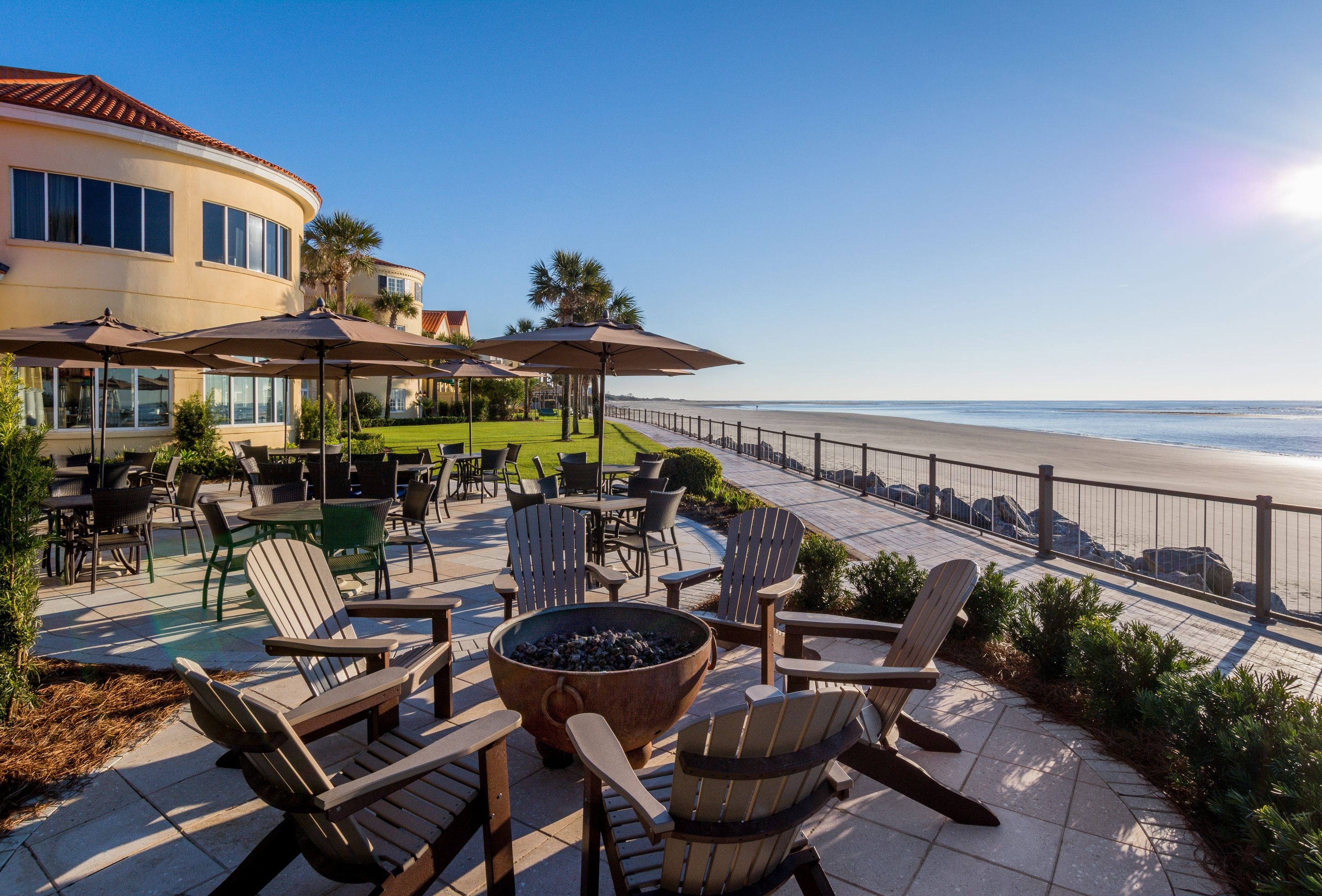 a patio with chairs and umbrellas by a beach
