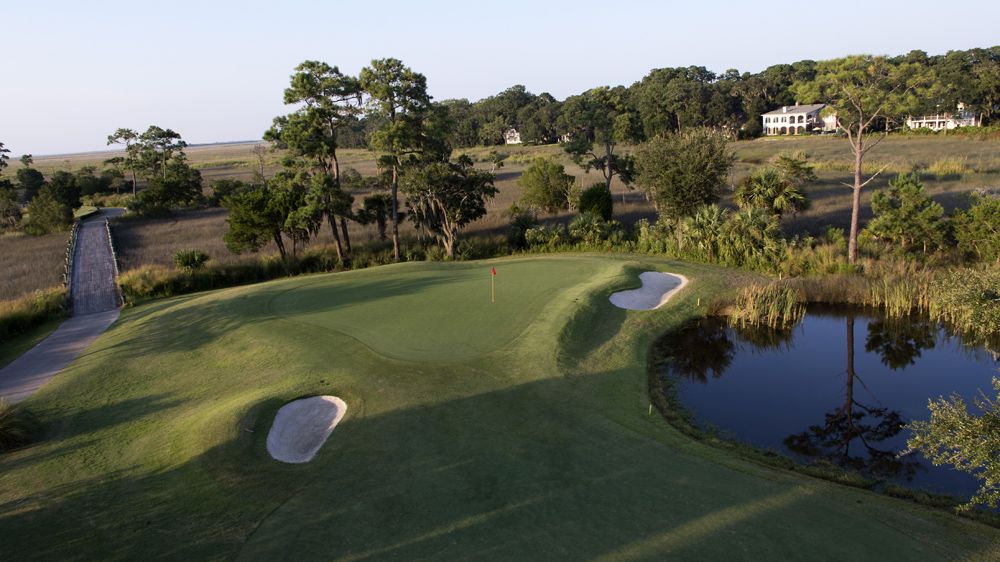 a golf course with a pond and a flag