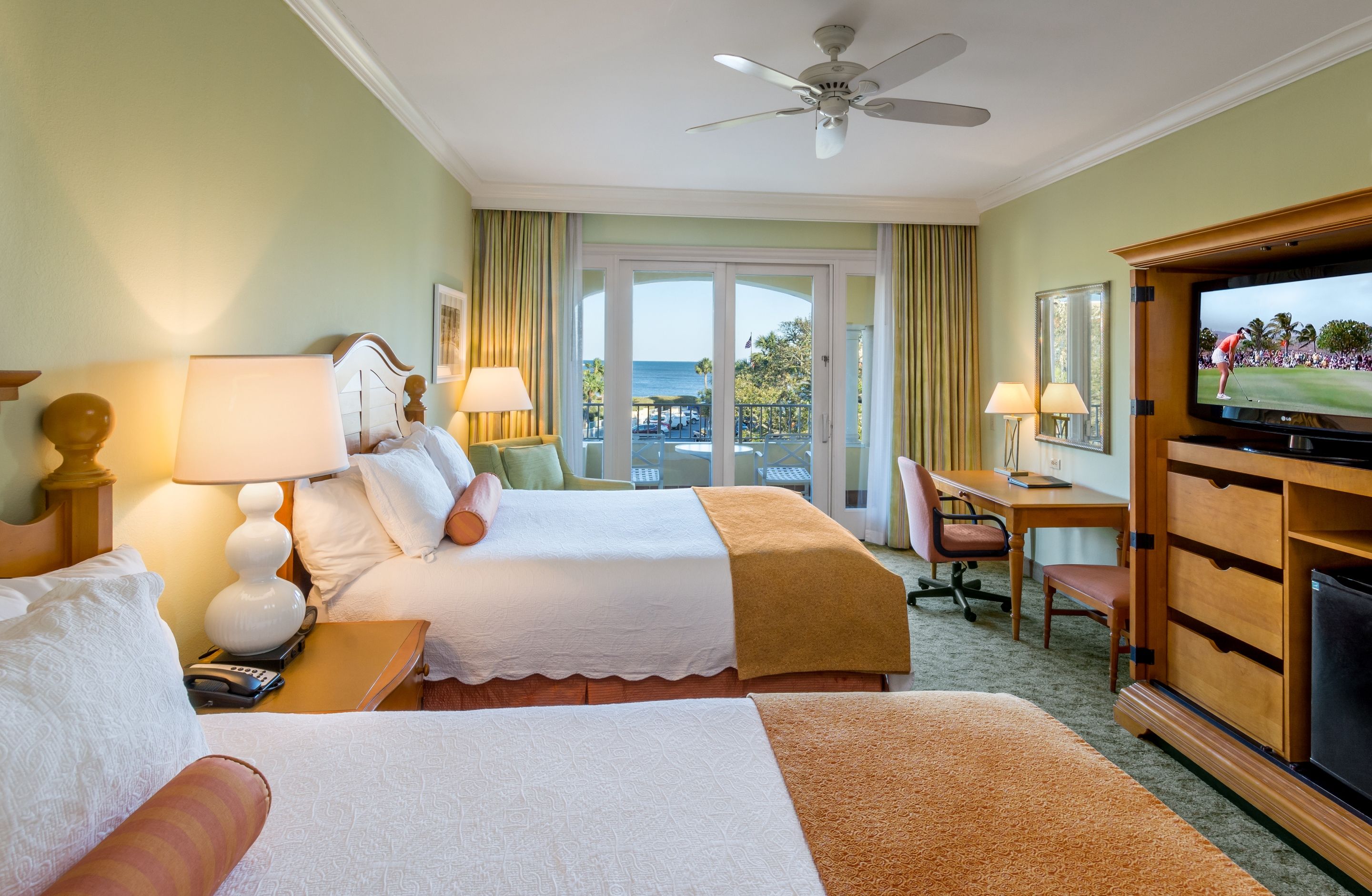a room with two beds and a desk and a fan