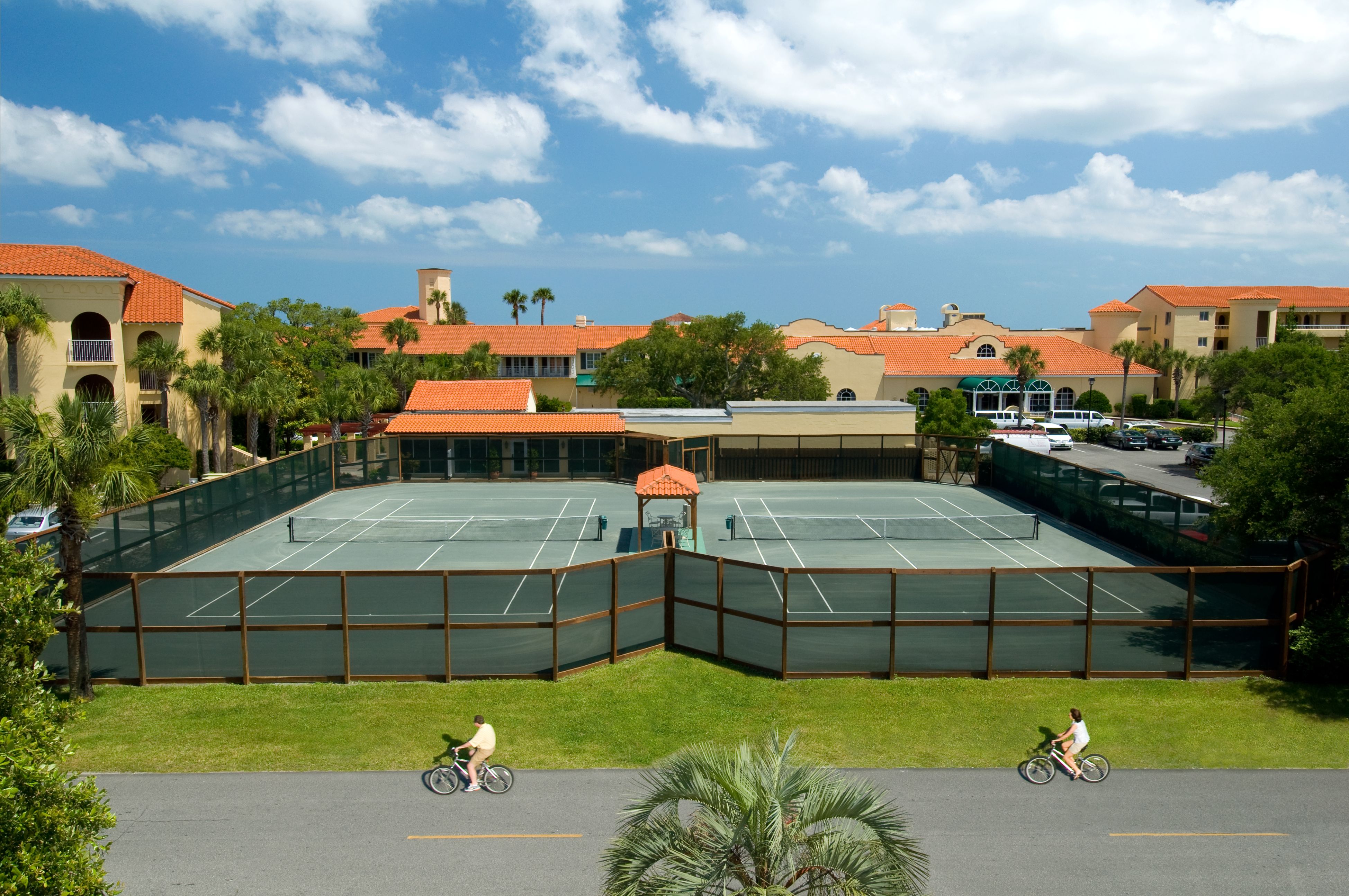 a tennis court with people riding bikes