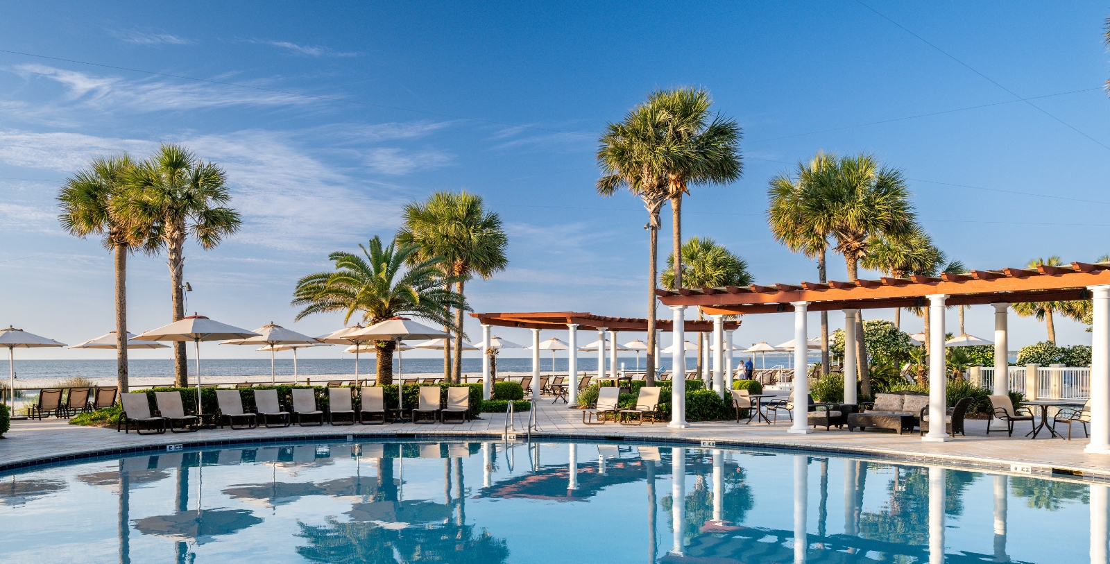 a pool with palm trees and umbrellas