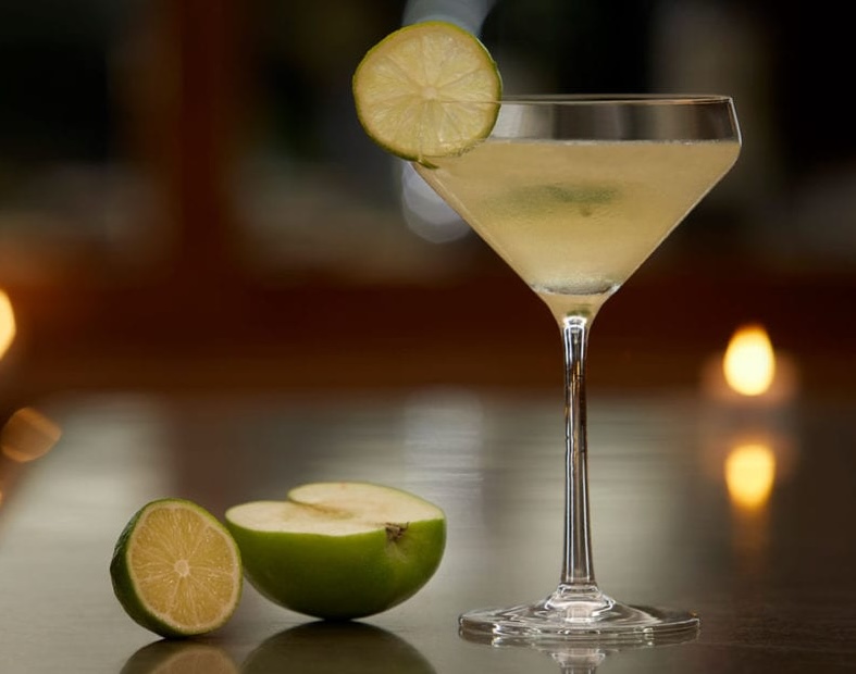 a glass with a drink and a lime slice next to it