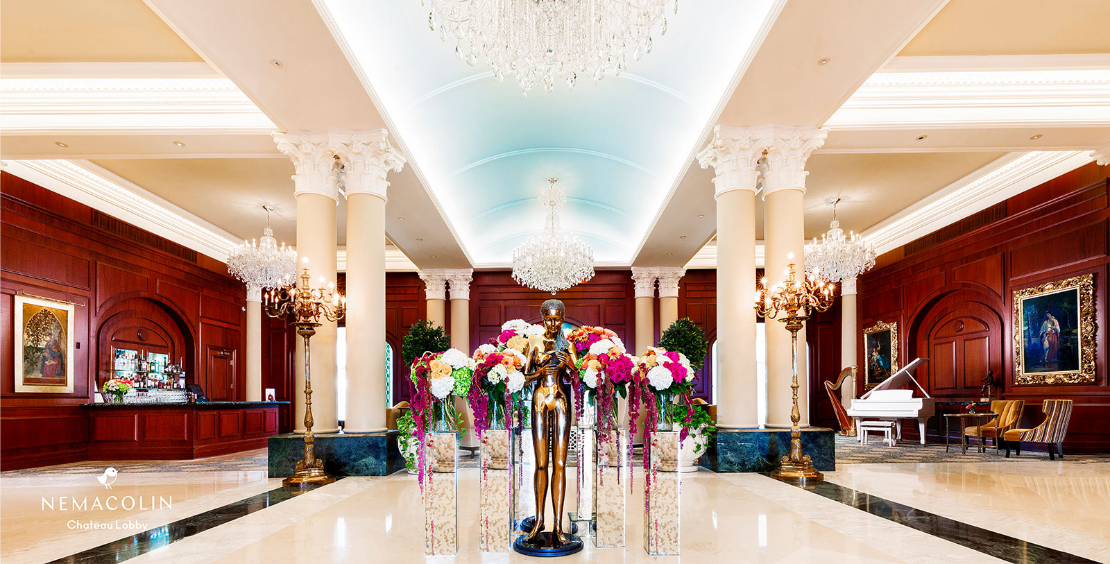 a statue in a hall with flowers and chandeliers