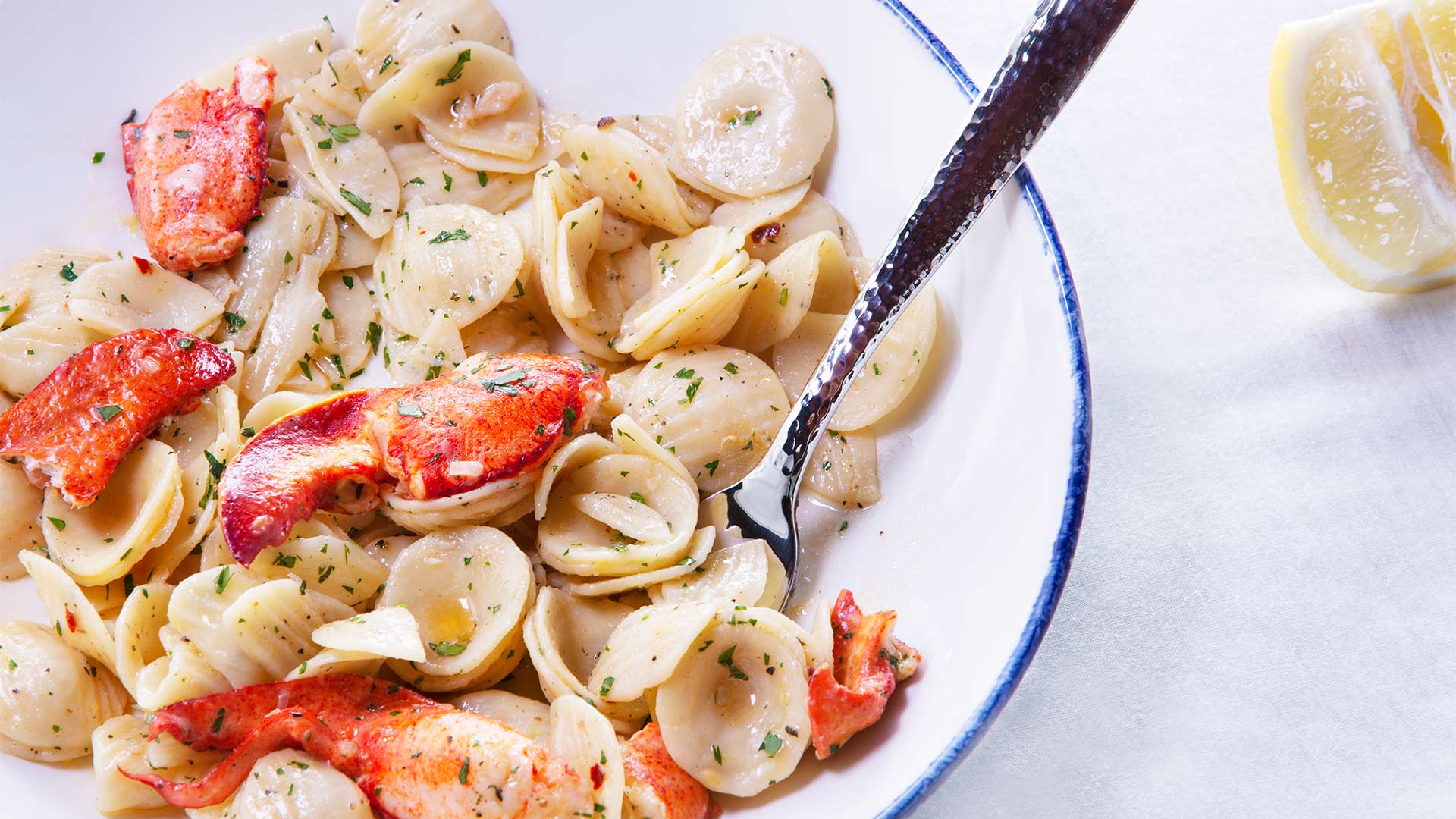 a plate of pasta with lobster and a fork
