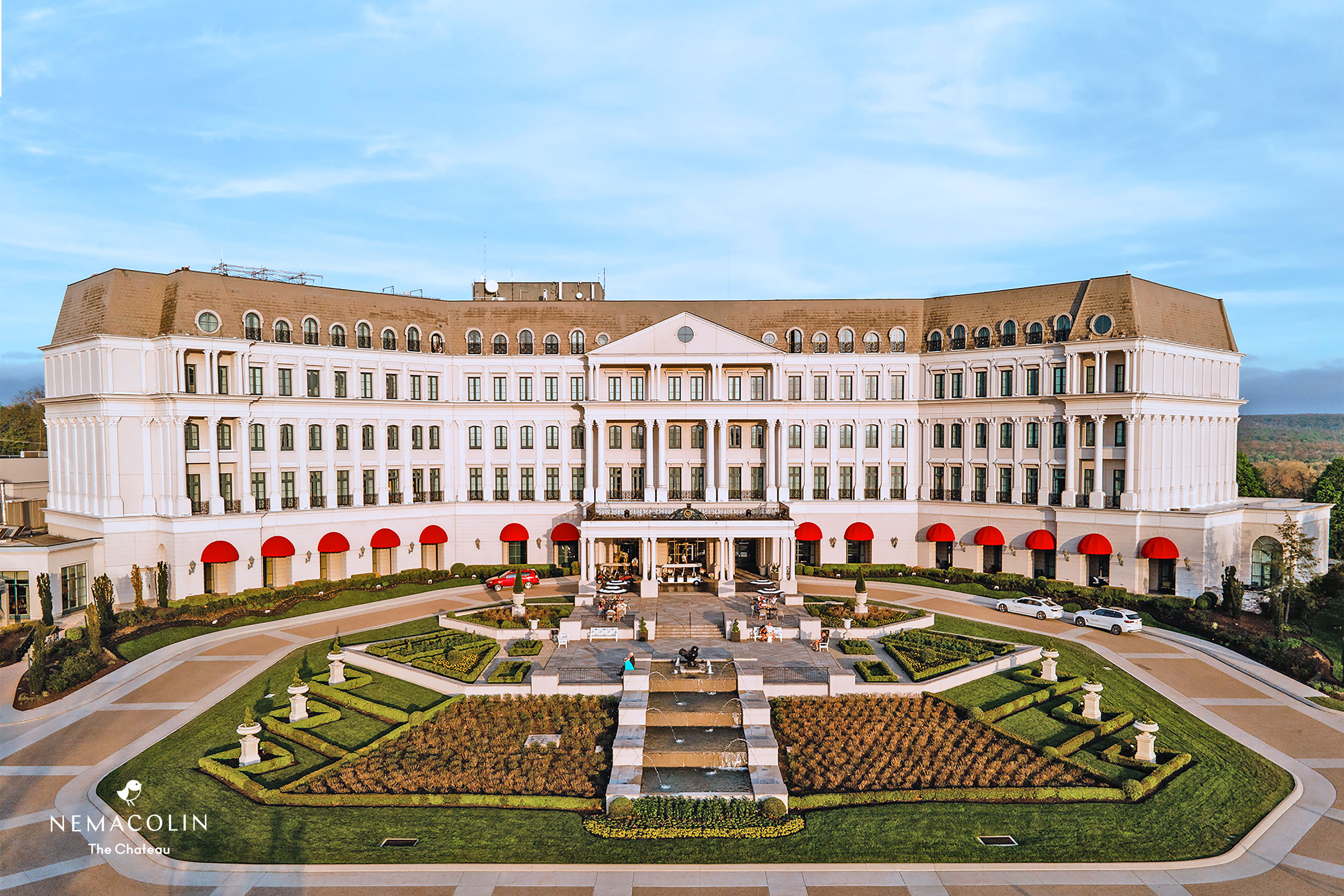 a large white building with a fountain and a garden