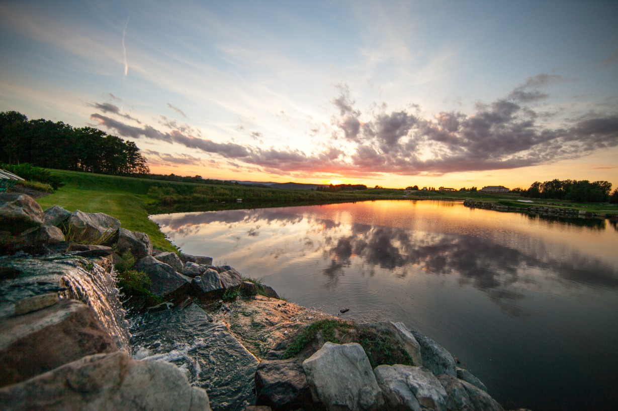 a body of water with rocks and a sunset