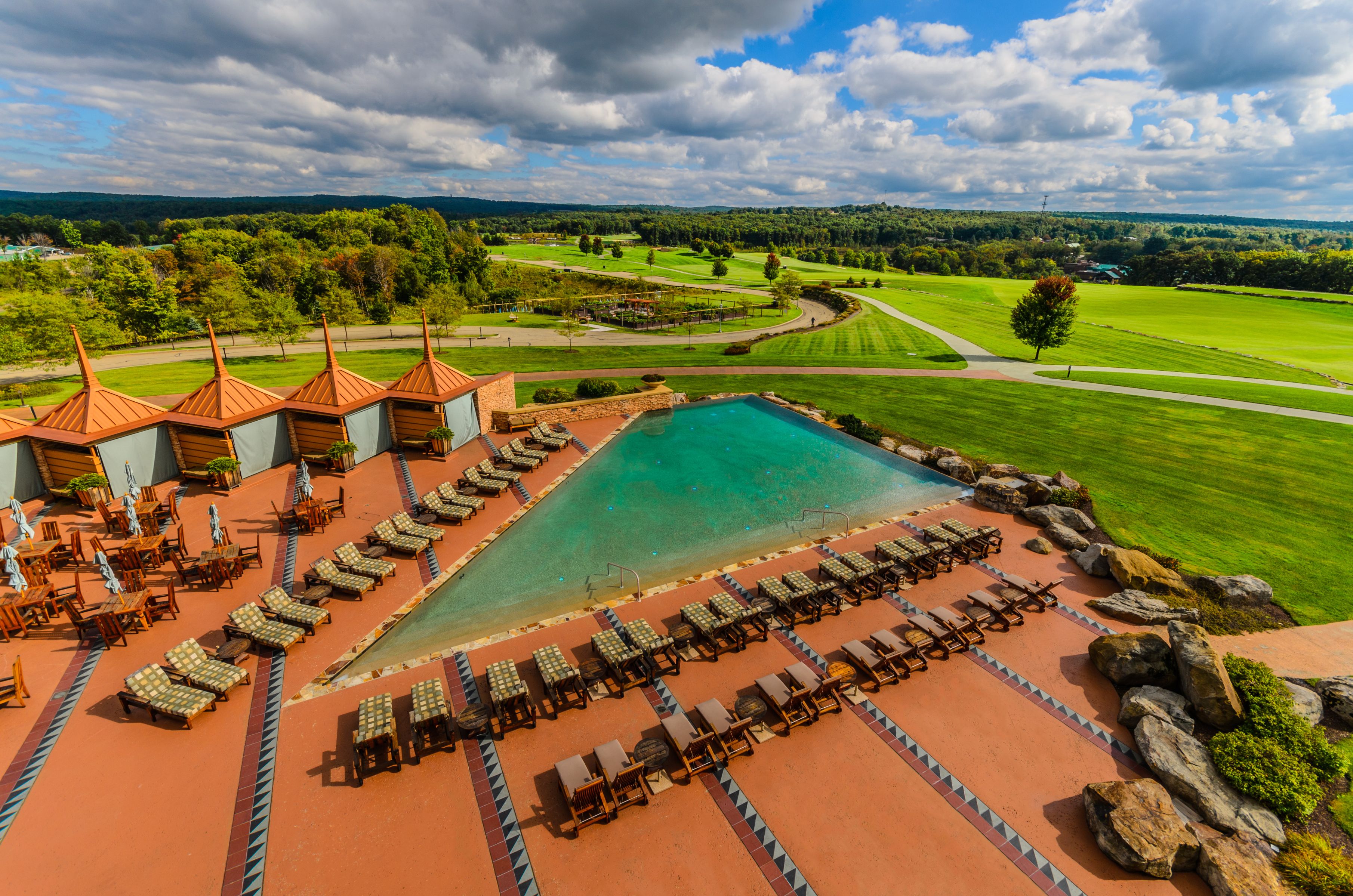 a pool with chairs and a pool in the middle of a resort