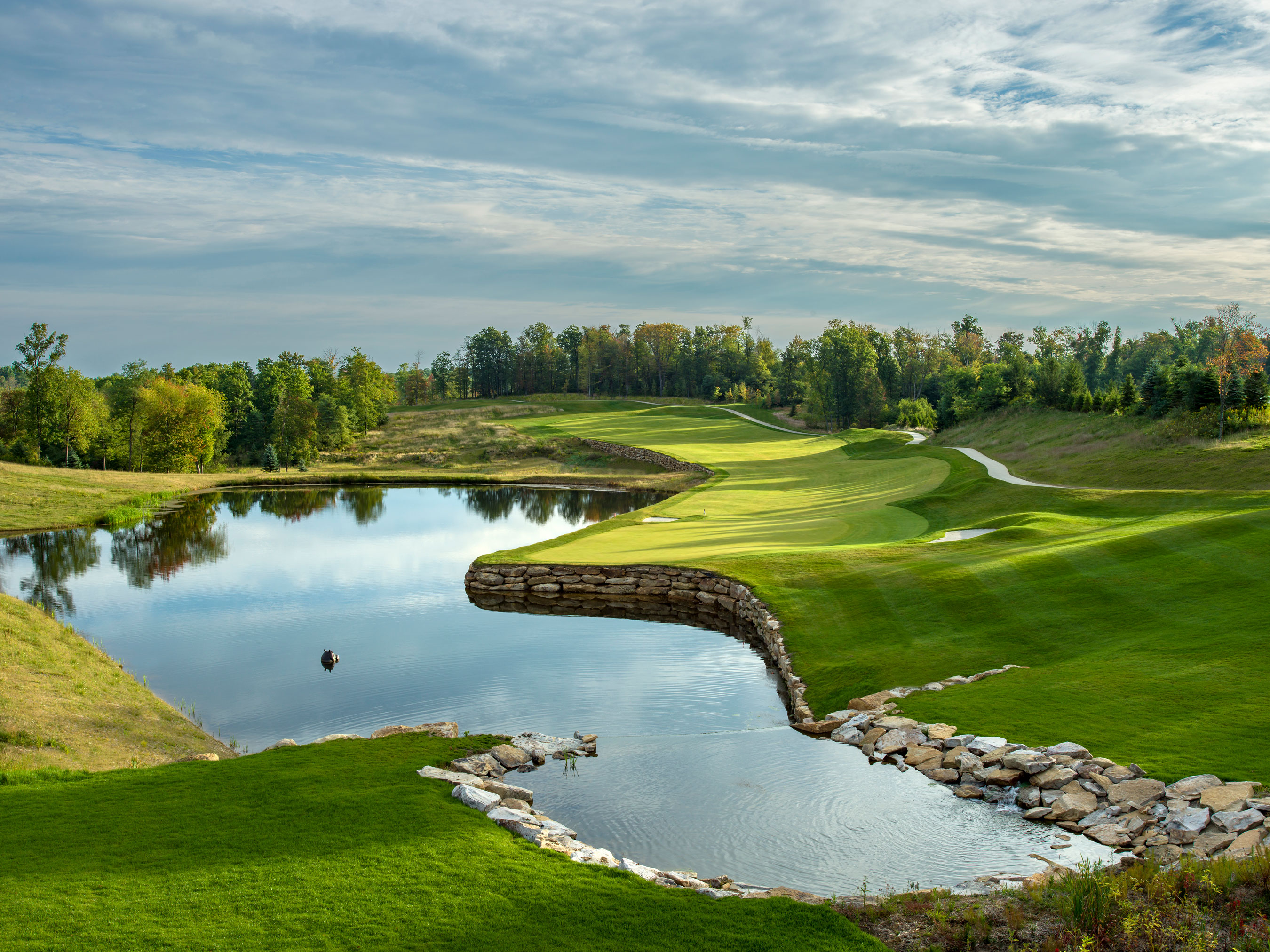a pond with a river in the middle of a golf course