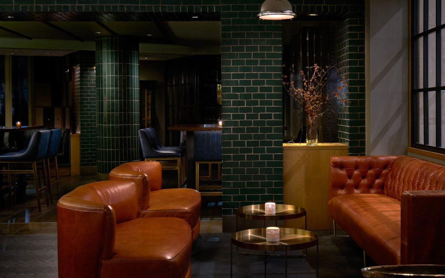 a room with a brick wall and brown couches