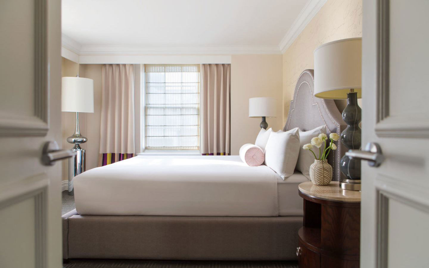 a bed with white sheets and lamps in a hotel room