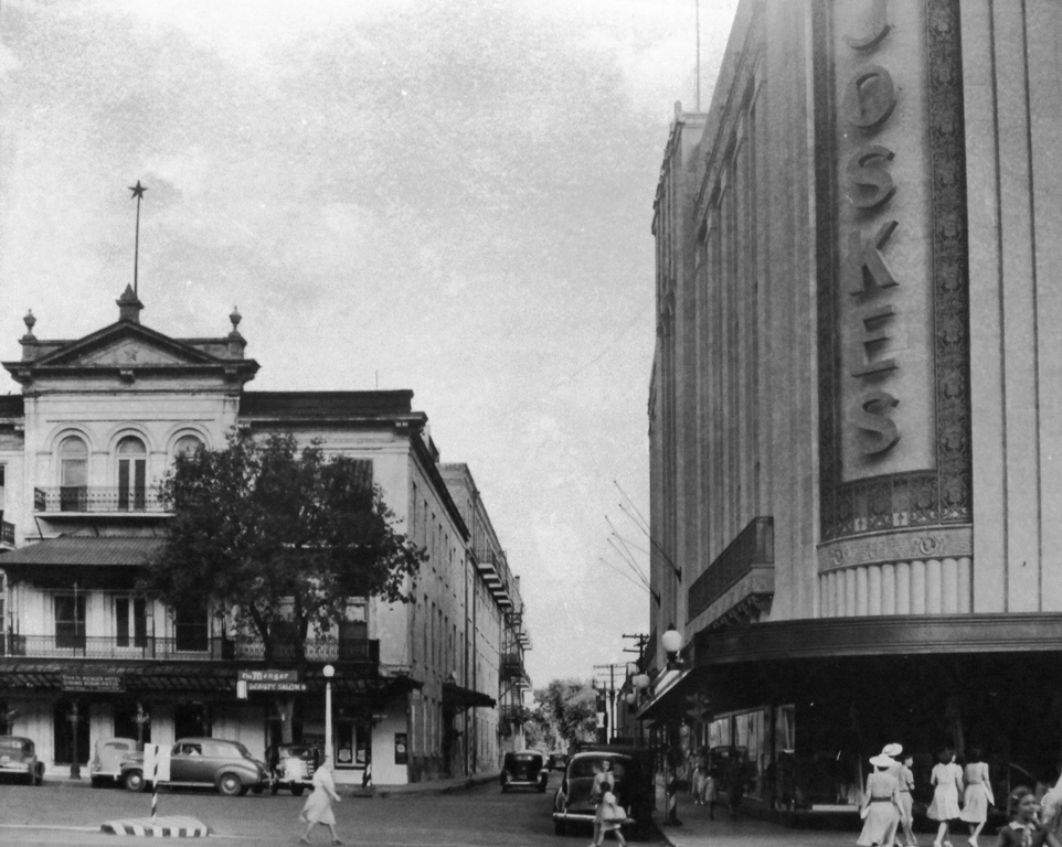 a black and white photo of a street with buildings and cars