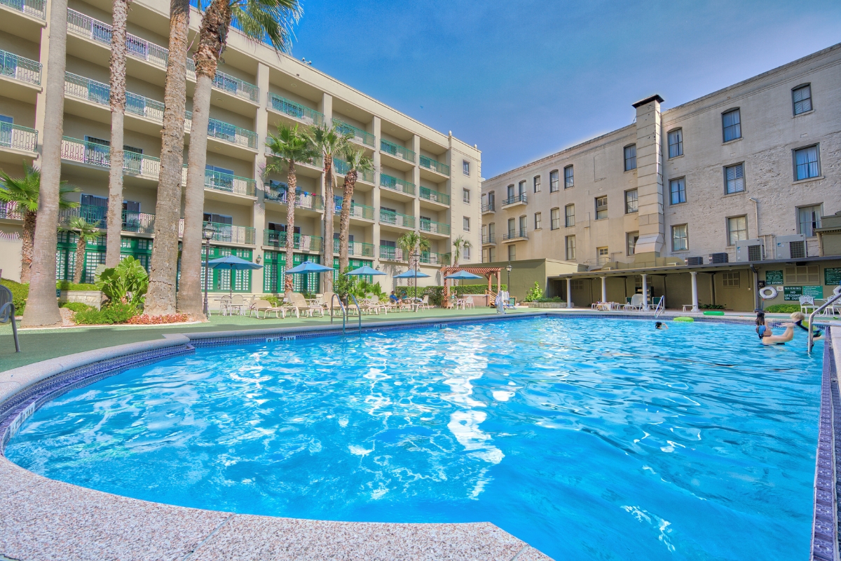 a swimming pool with palm trees in front of a building