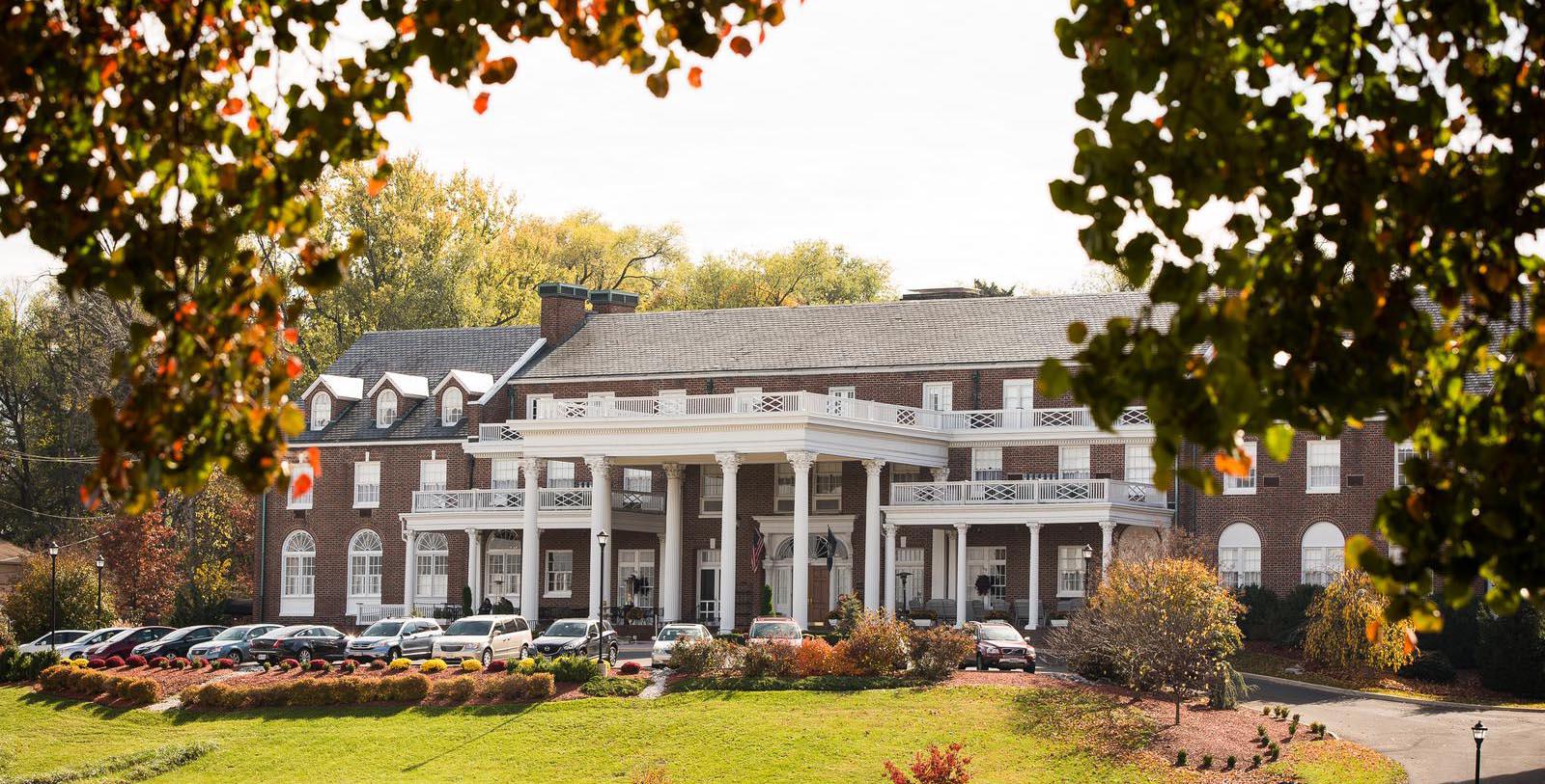 a large brick building with white pillars and a lawn