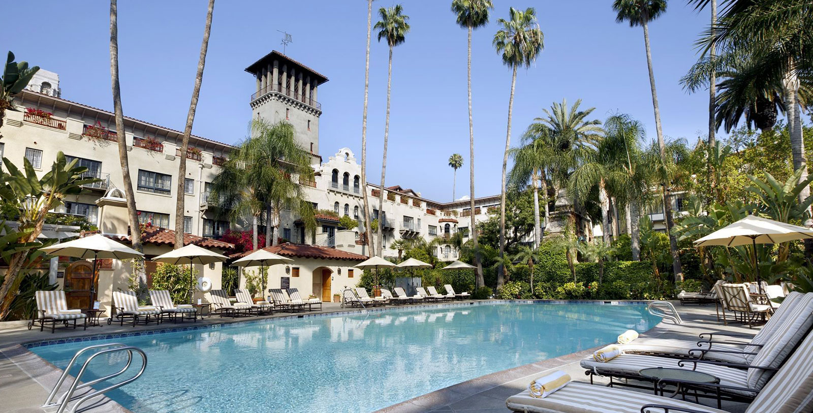 a pool with palm trees and a building