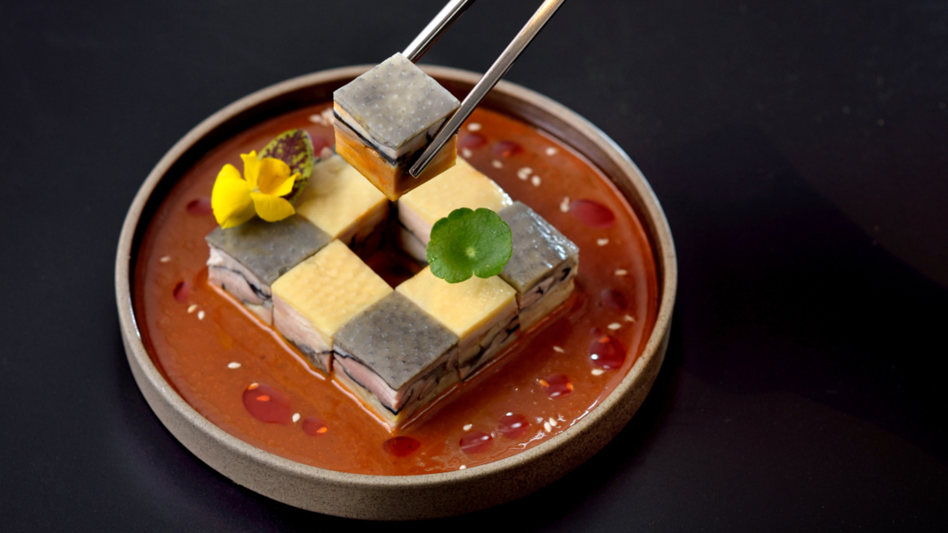 a pair of chopsticks holding food in a bowl