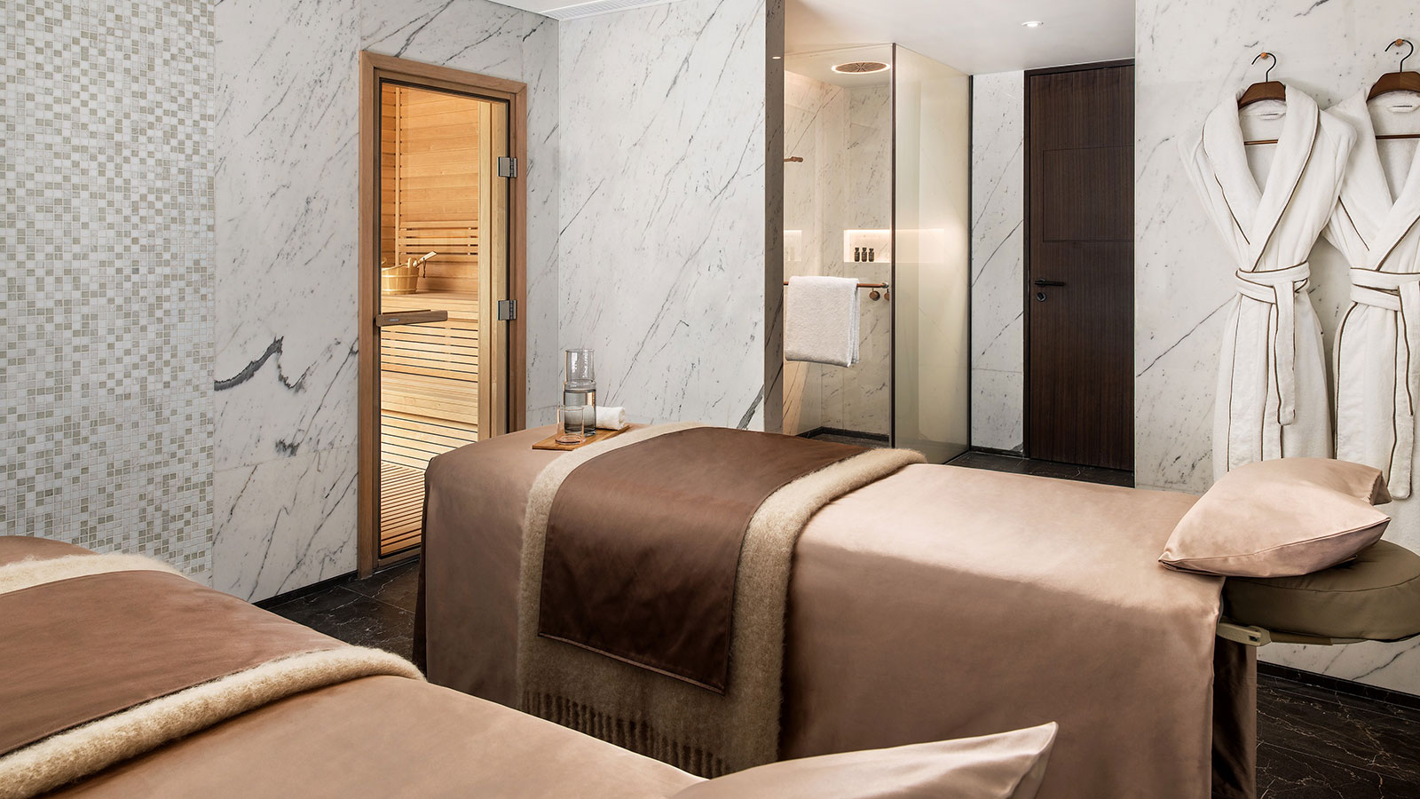 a massage room with a wooden door and a glass shower