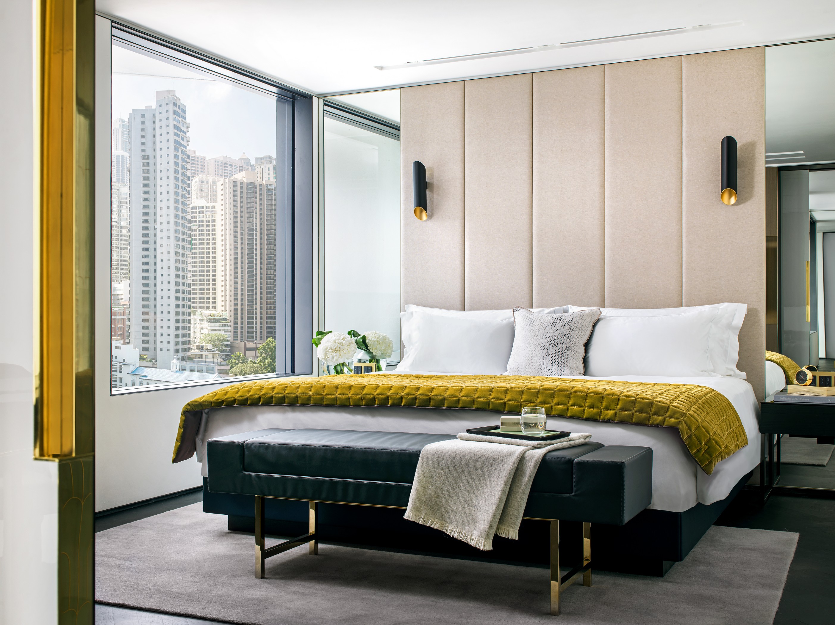 a bed with a bench and a bench in a room with tall windows