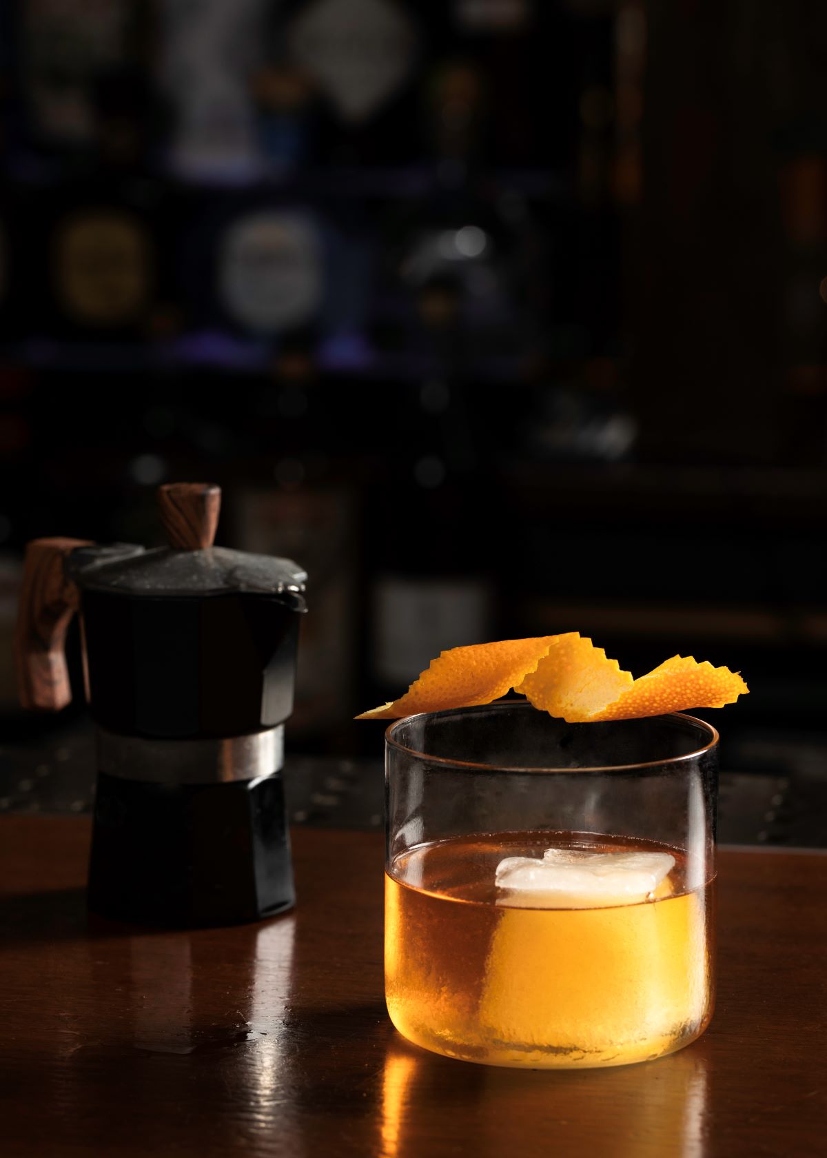 a glass of liquid with orange peels on top of it