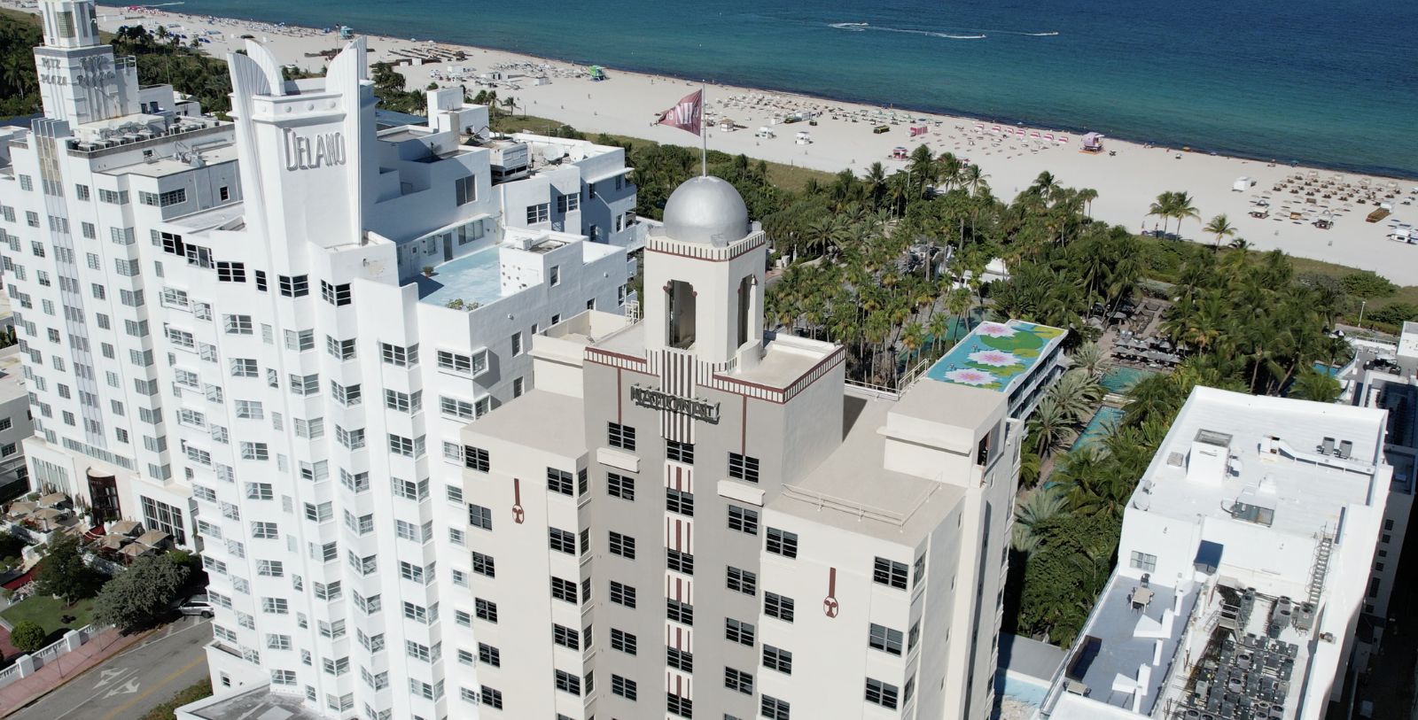a tall building with a flag on top and a beach in the background