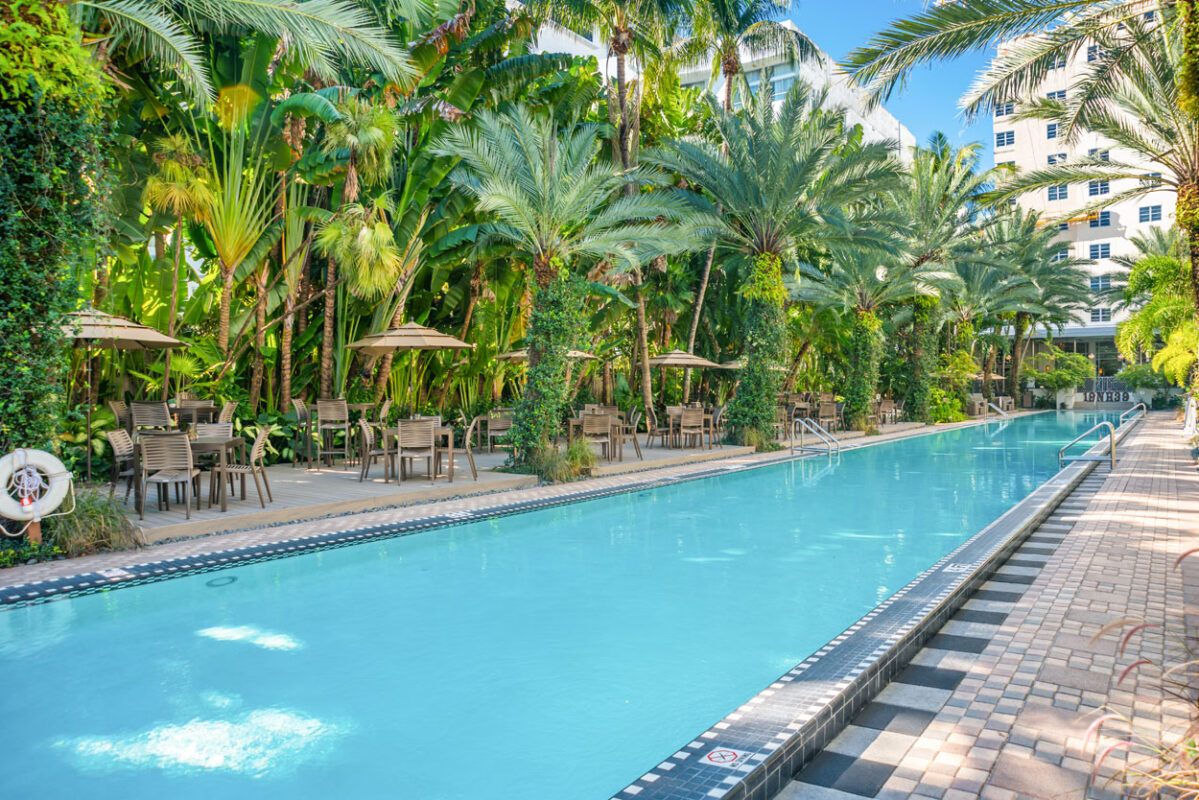 a pool with chairs and tables and trees