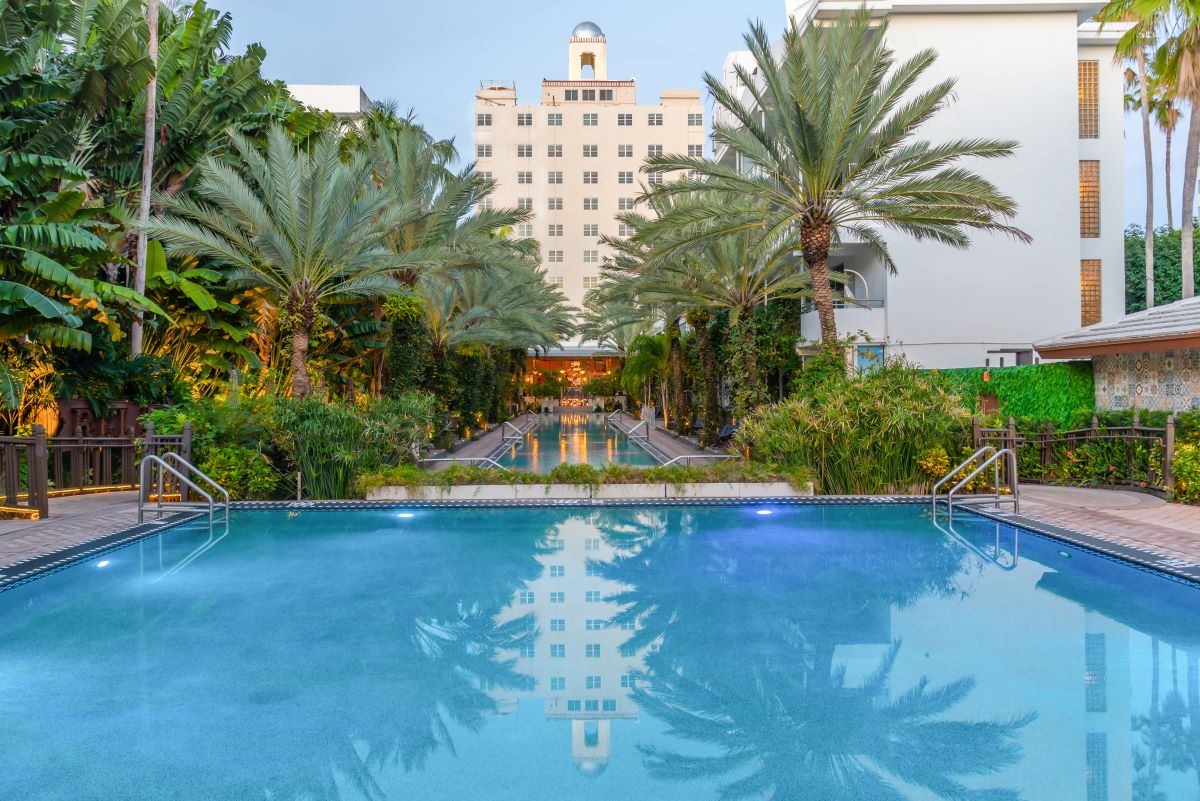 a pool with palm trees and buildings in the background