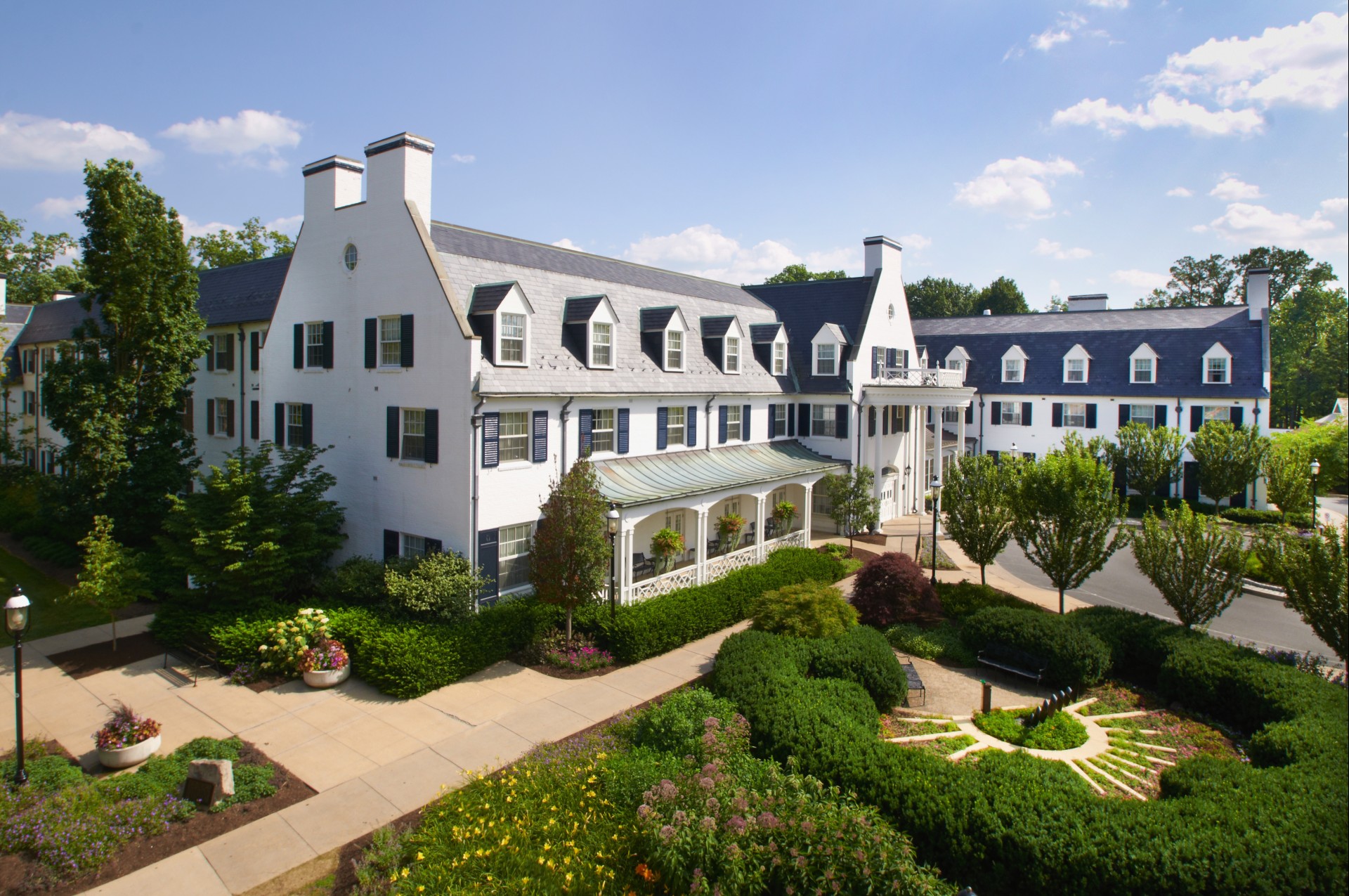 a large white building with a garden and trees