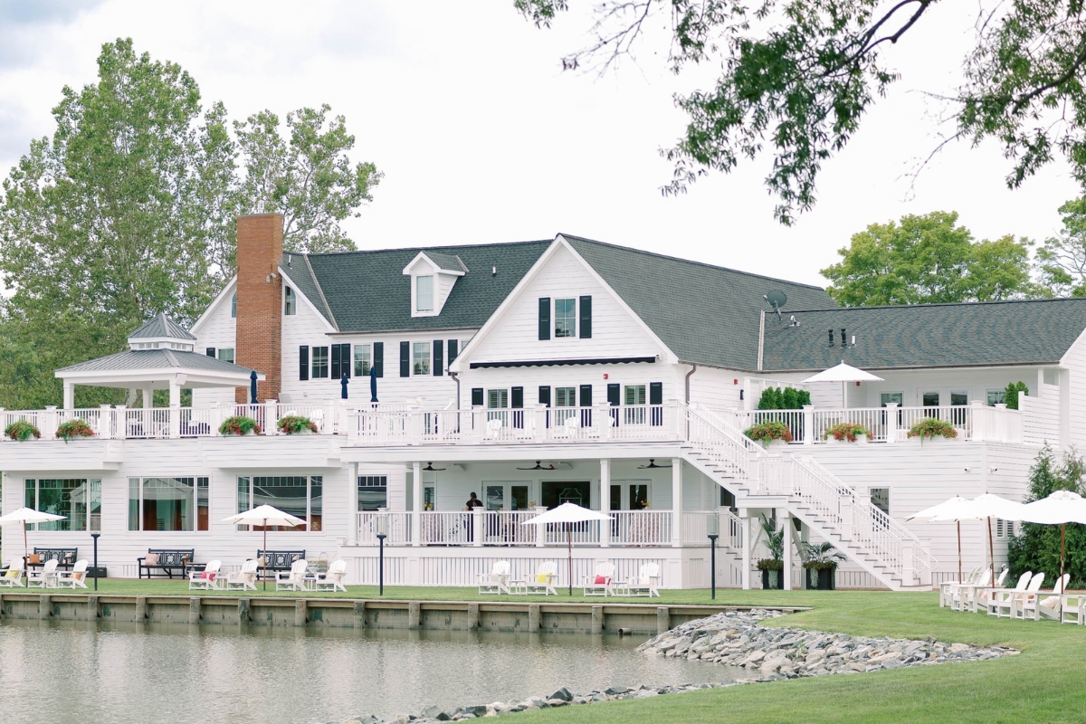 a large white house with a lake and trees
