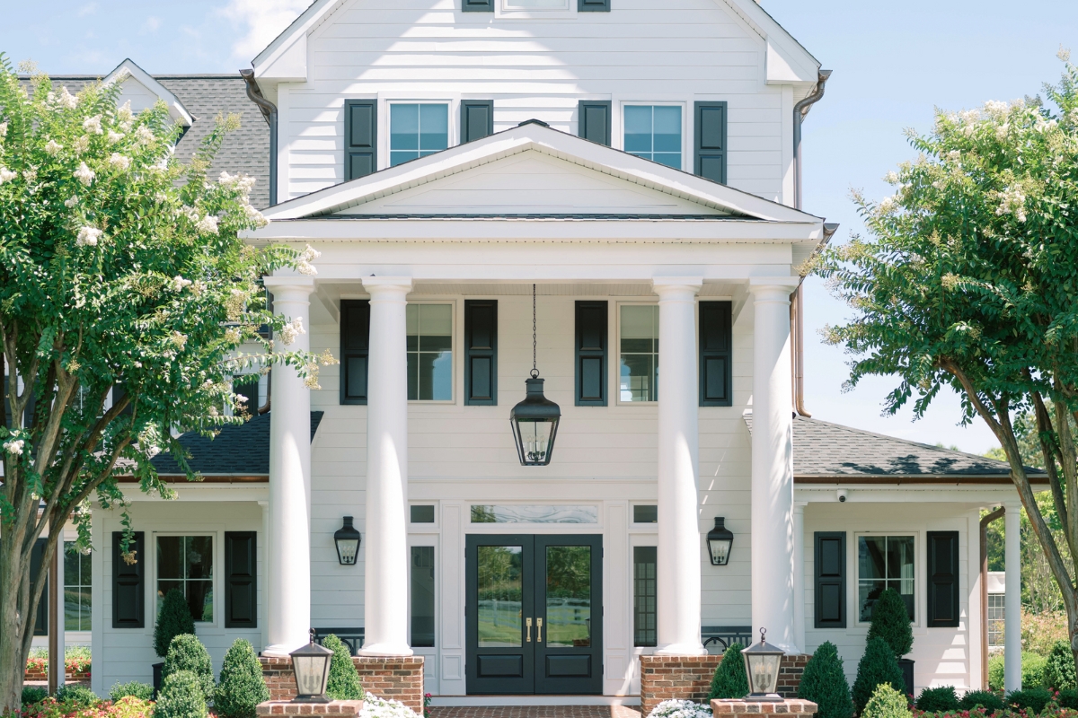 a white house with columns and a black door