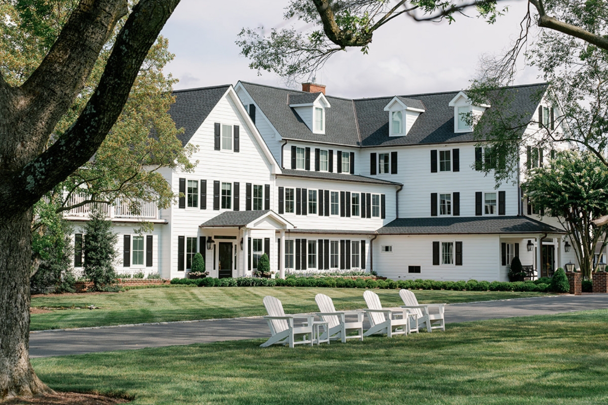a large white house with lawn and chairs
