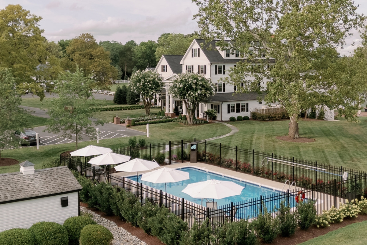 a pool with umbrellas and a fence in front of a house