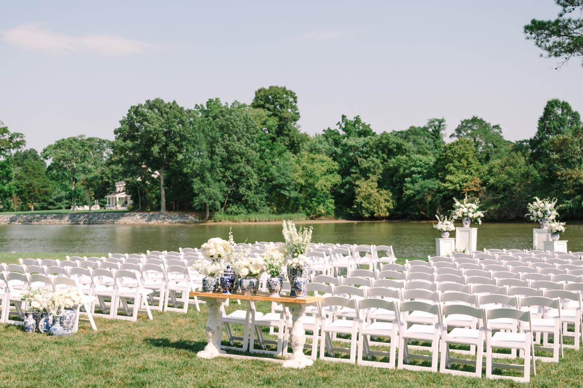 a row of white chairs with white chairs and a table with flowers