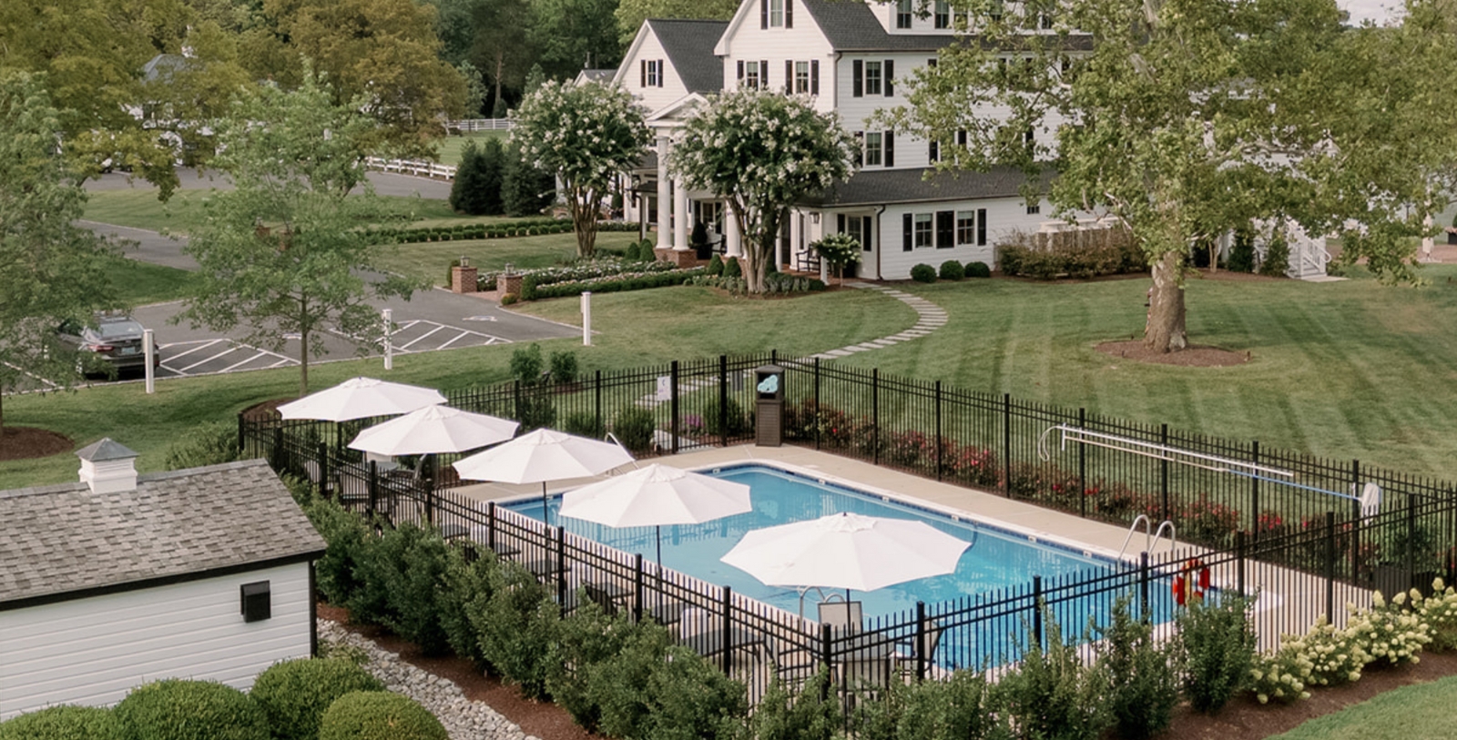 a pool with umbrellas and a fence in front of a house