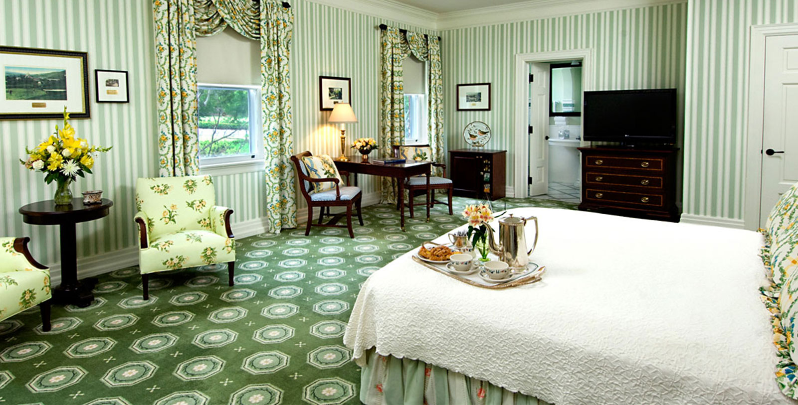 a room with green striped walls and a bed with a tray of food