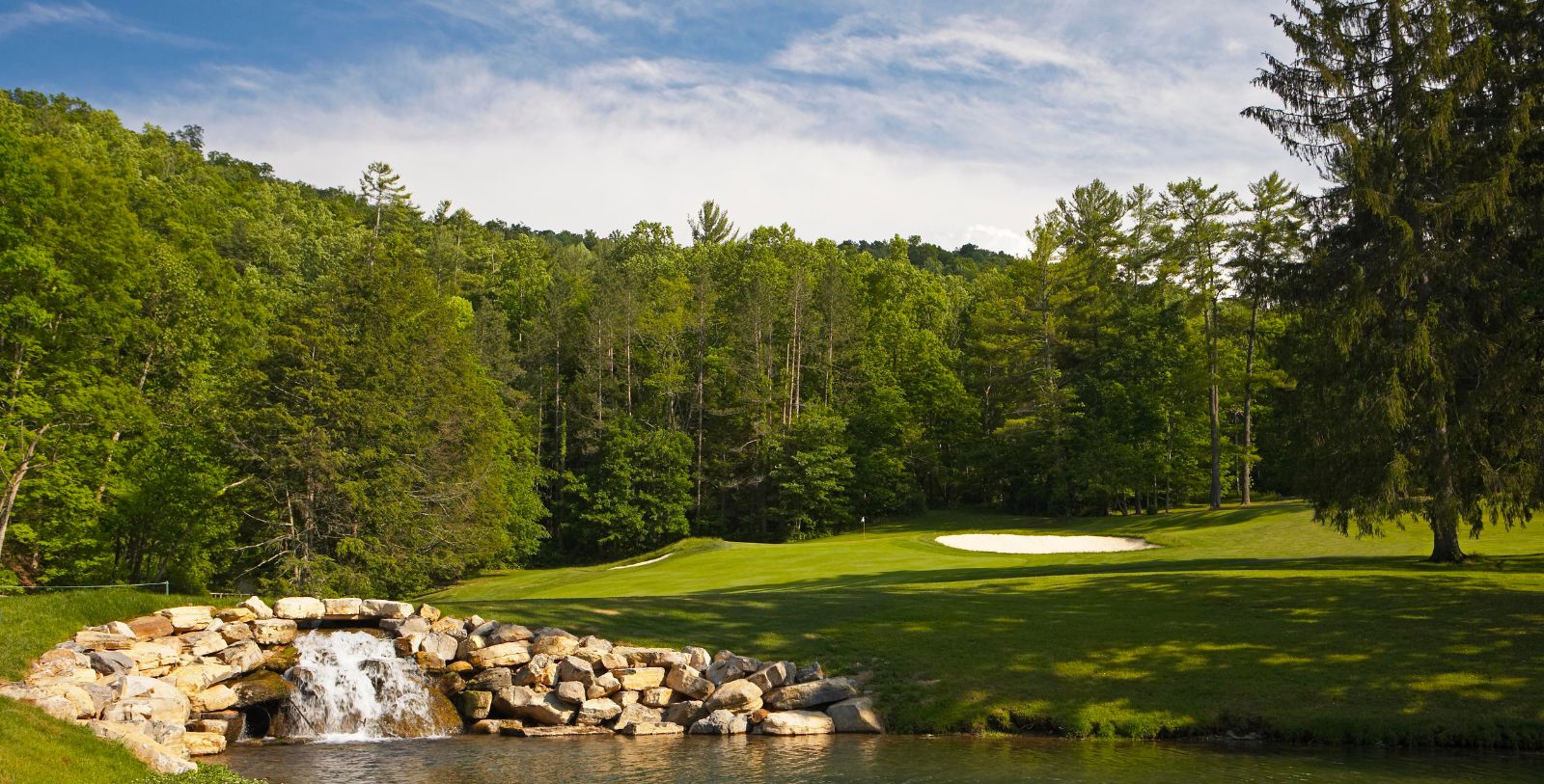 a golf course with a waterfall and rocks