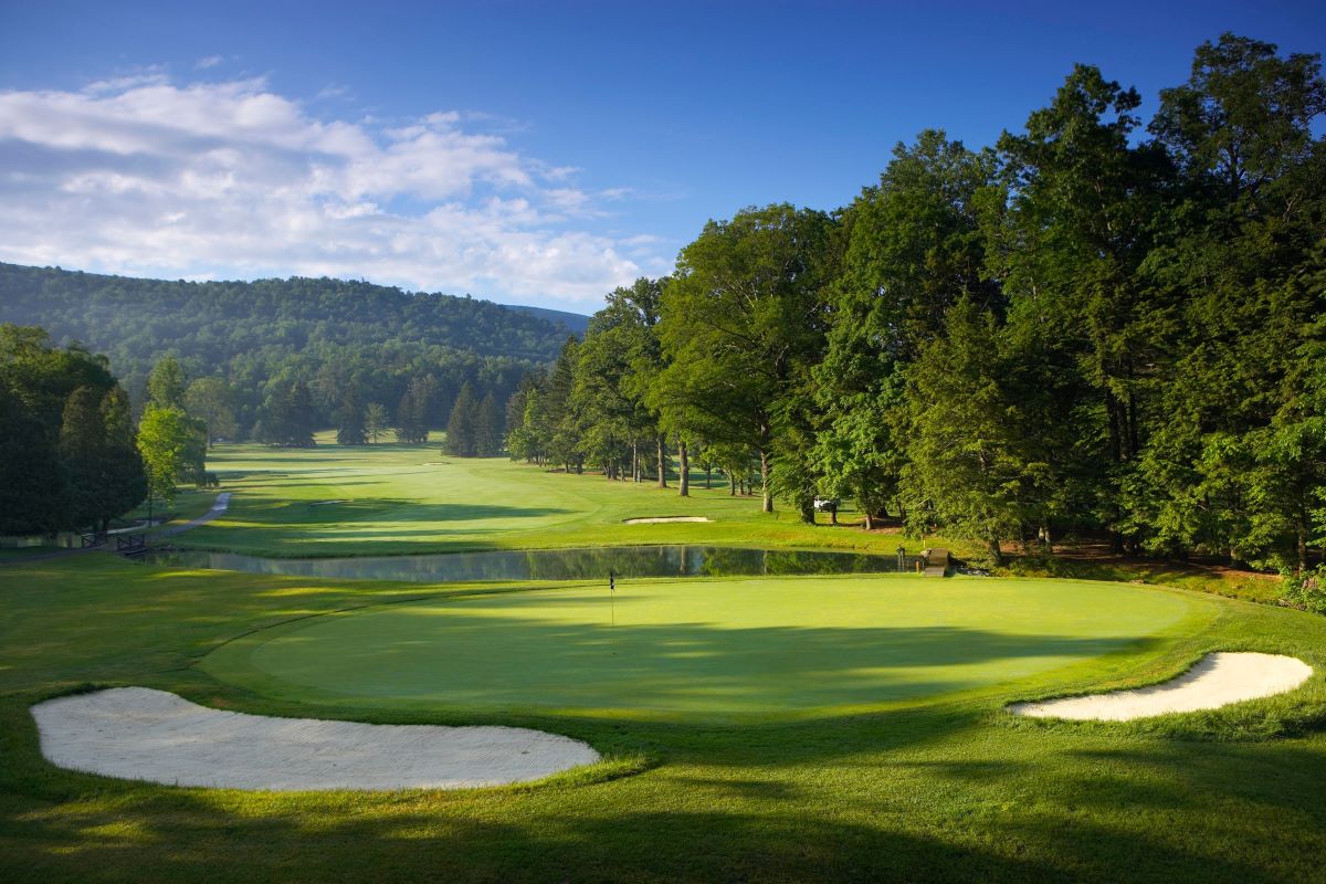 a golf course with a green field and trees