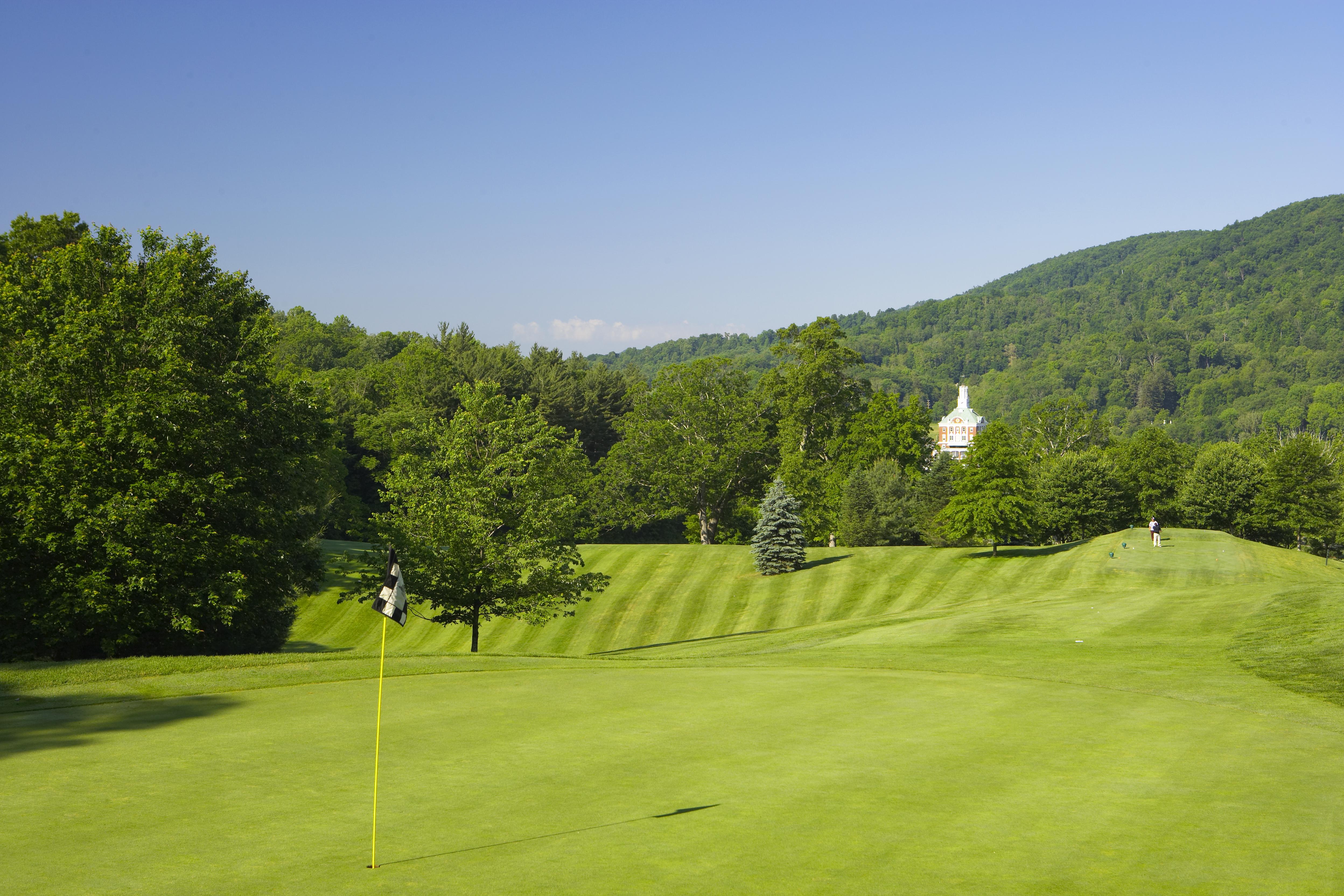 a golf course with trees and a building in the background