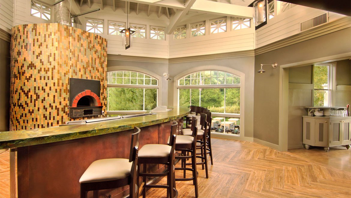 a bar with chairs in a room with windows