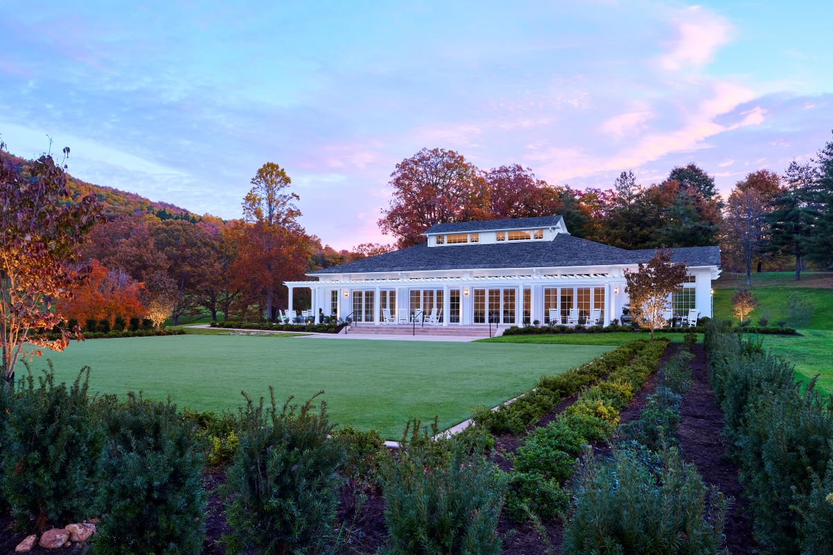 a large white building with a lawn and trees in the background