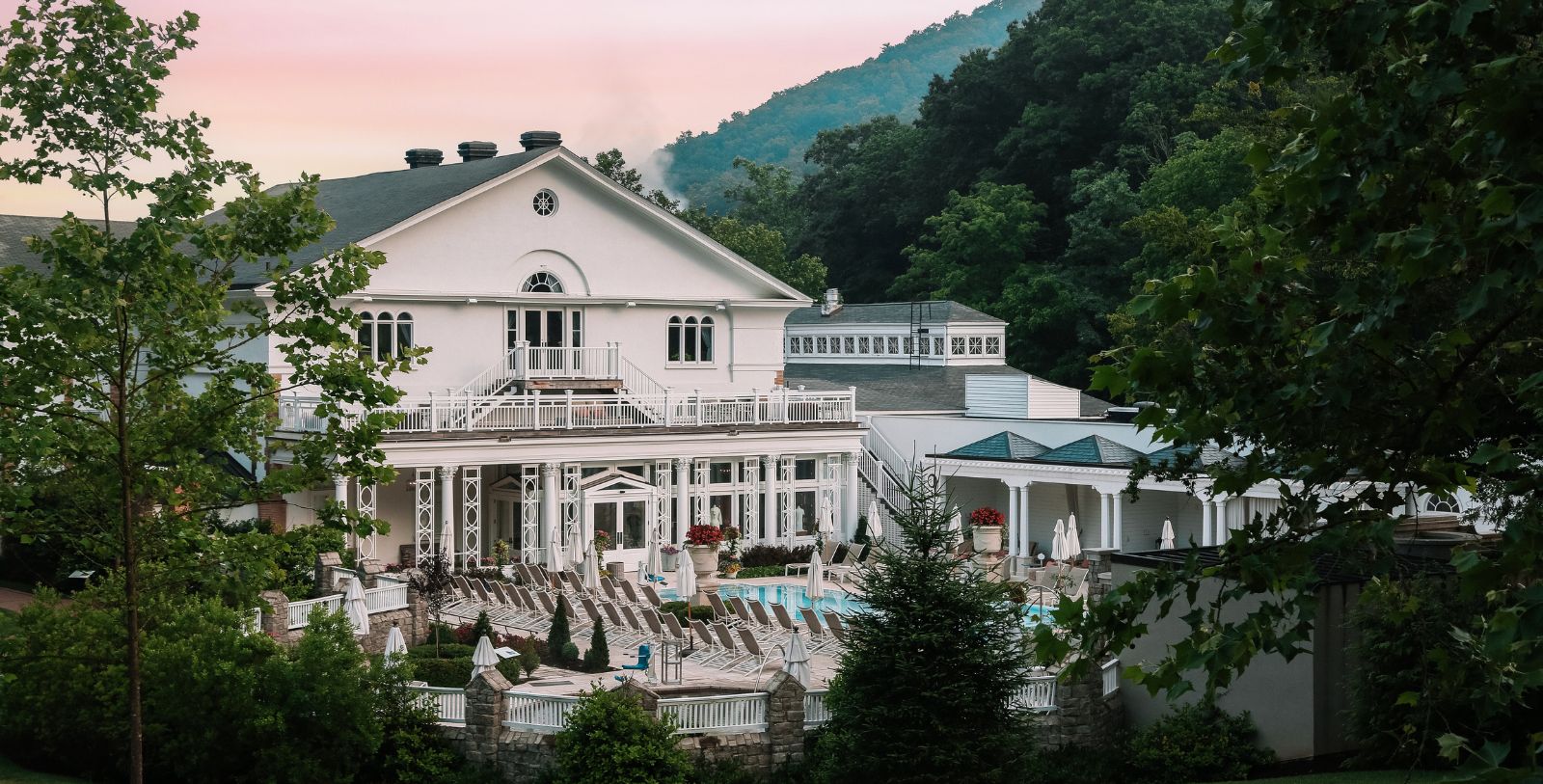 a large white building with a pool and trees