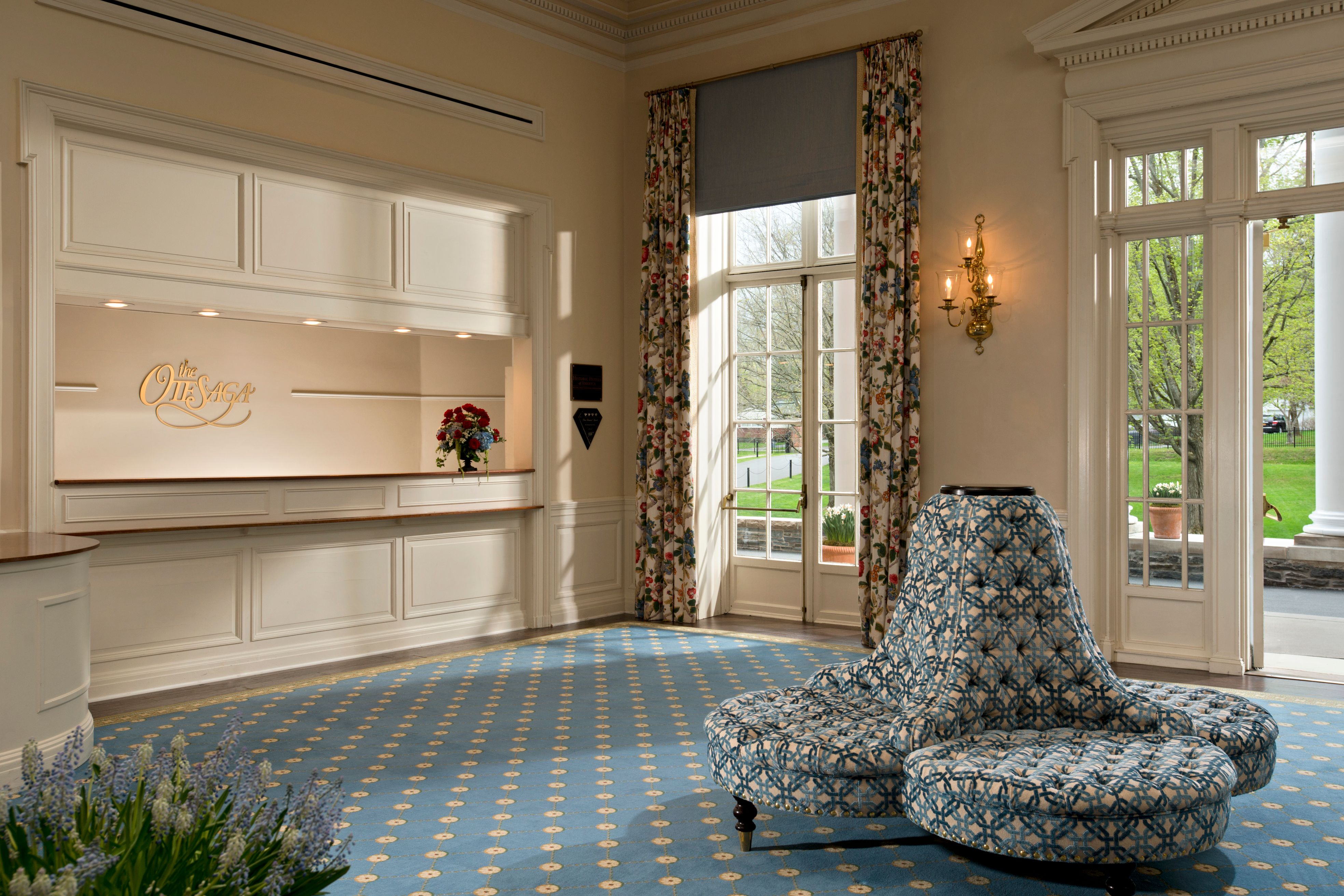 a room with a blue patterned chair and a window