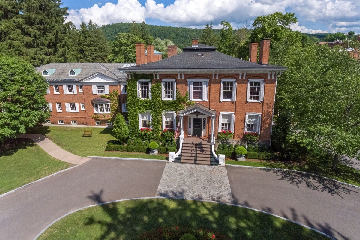 a large brick building with a driveway and trees