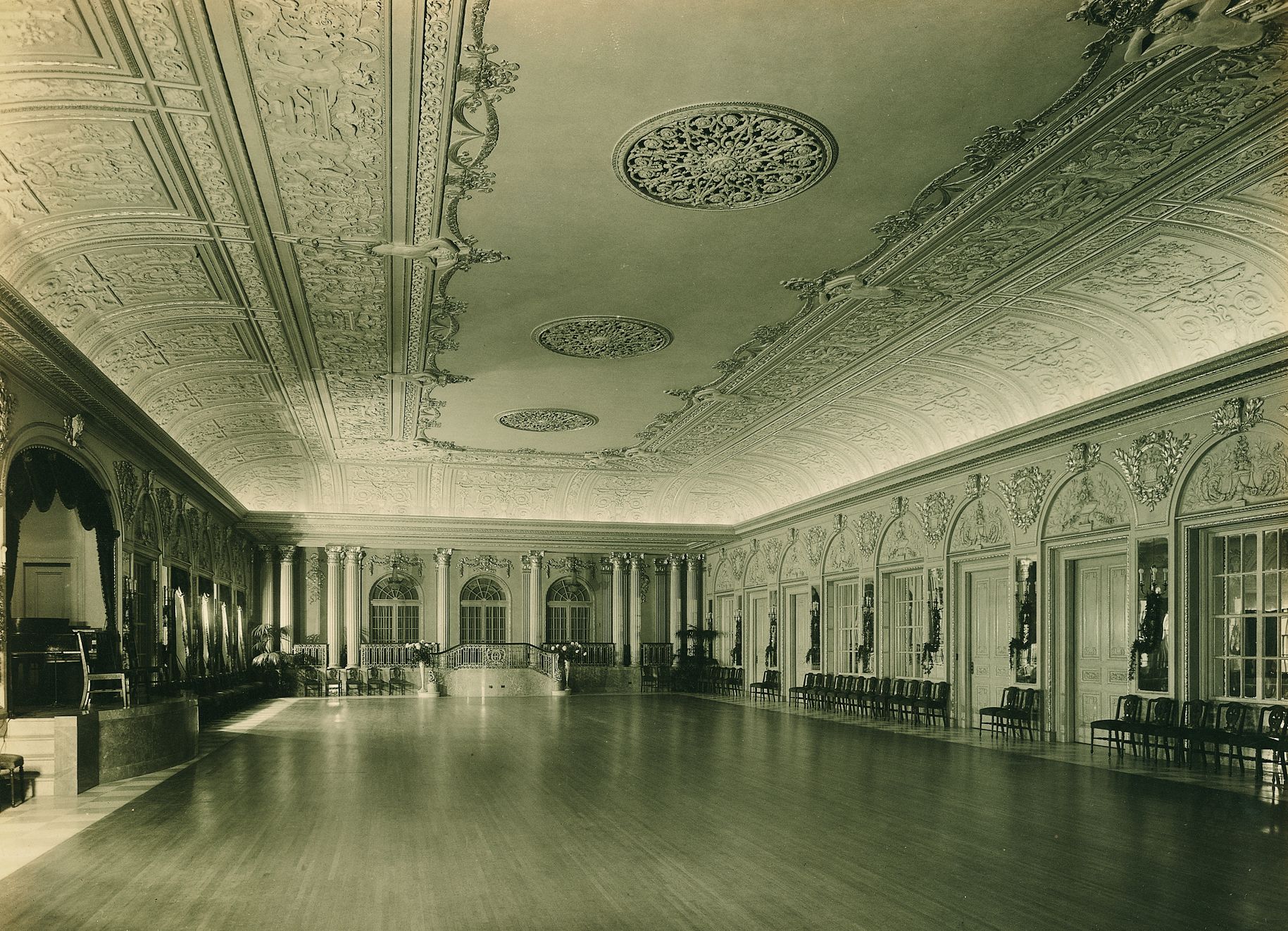 a large room with ornate ceiling and wood floor