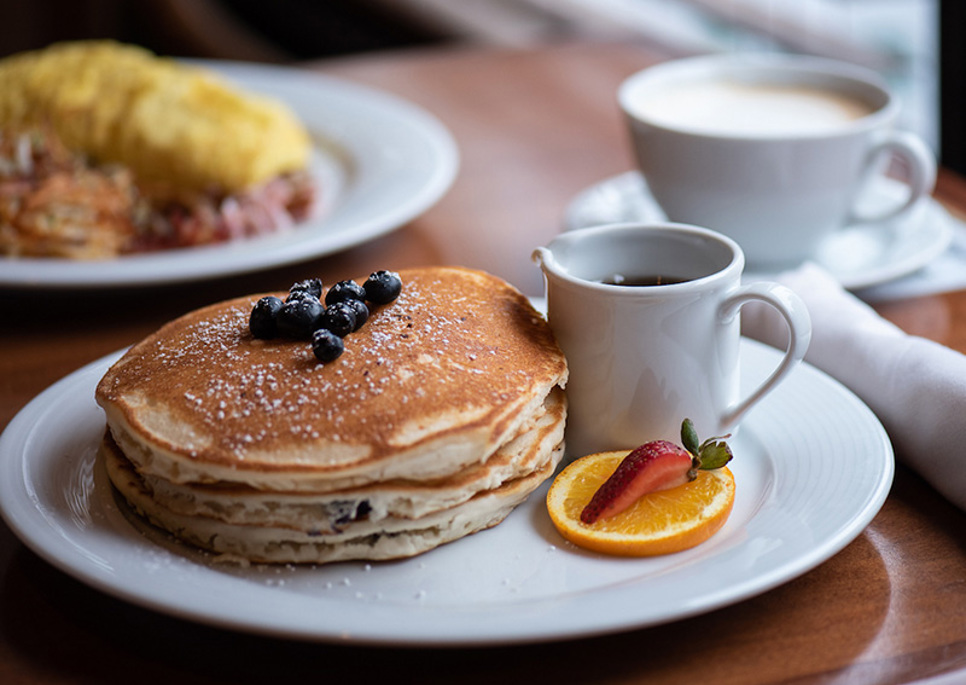 a plate of pancakes with fruit and a cup of coffee