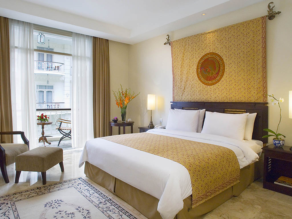 a bed with a patterned bedding and a stool in a room with a balcony