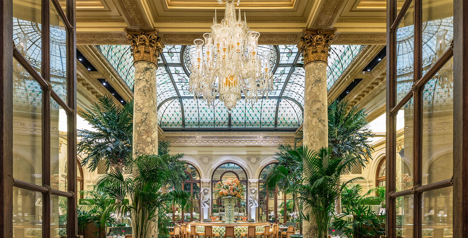 a chandelier in a room with columns and plants
