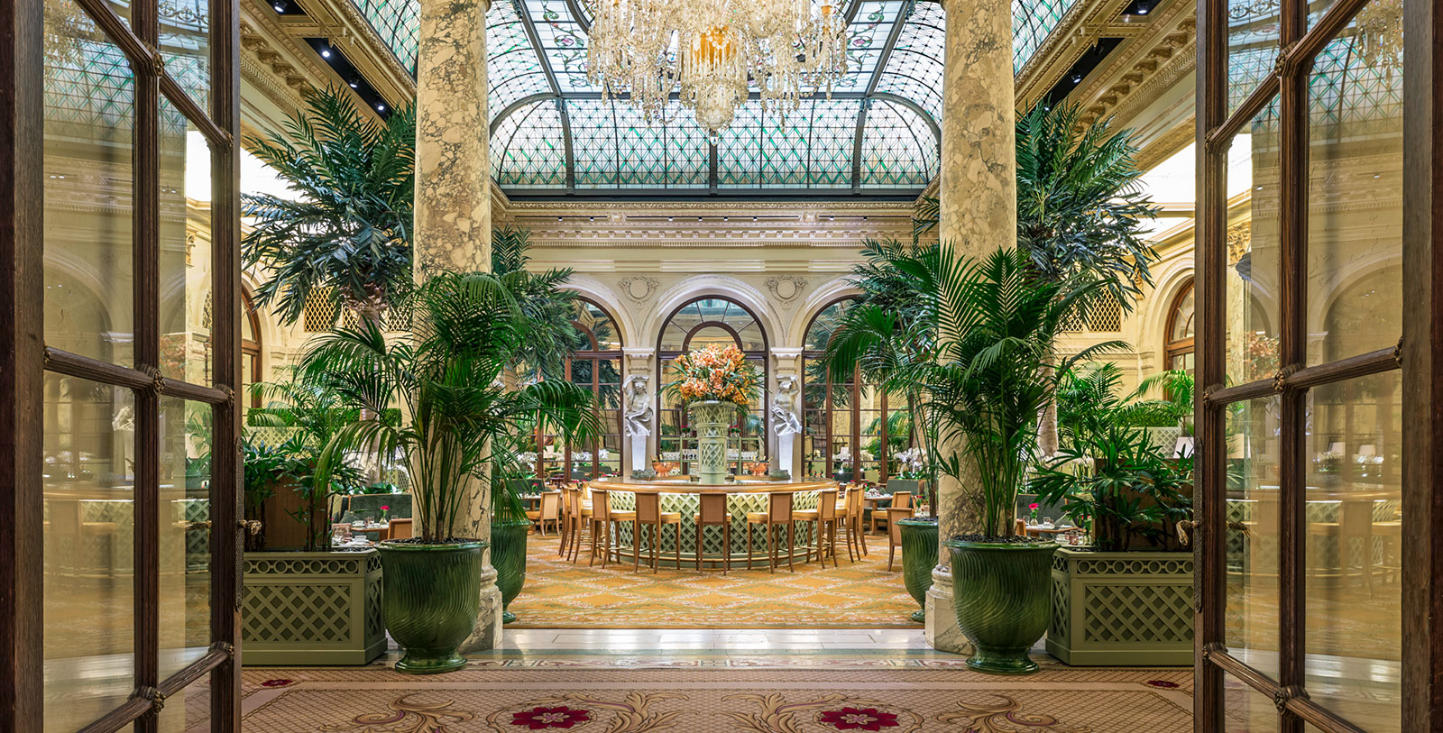 a room with a glass ceiling and a large round table with a chandelier
