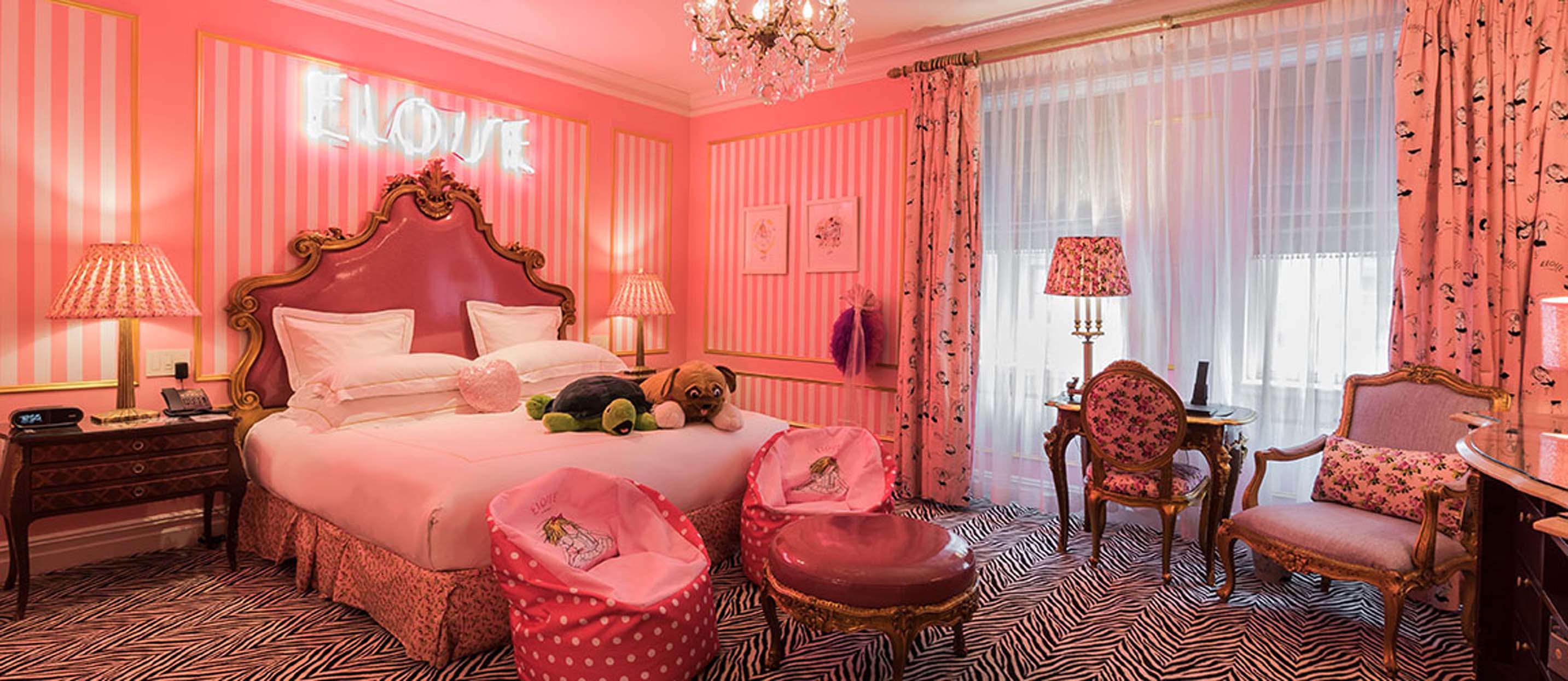 a room with pink walls and a bed and chairs