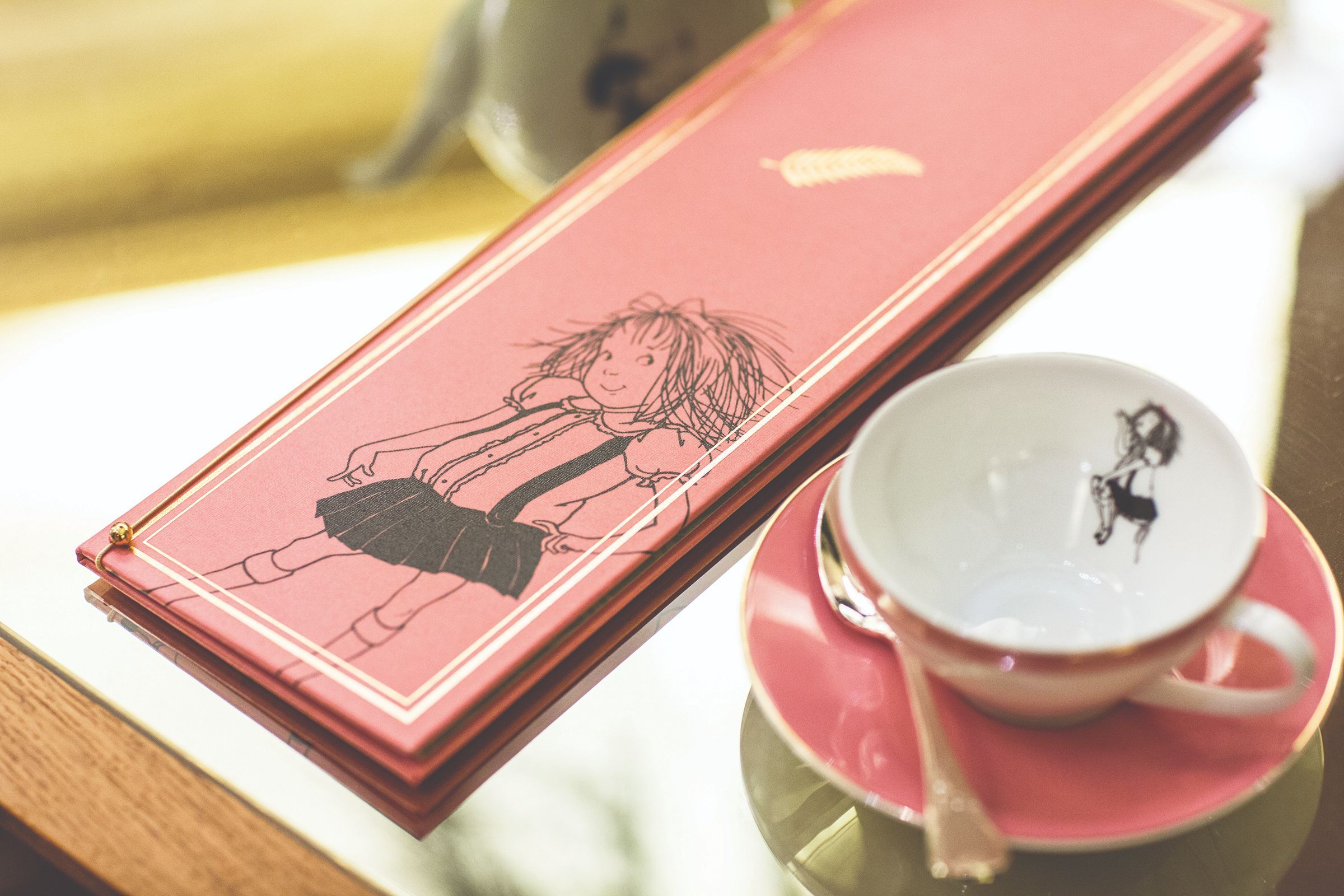 a pink box with a cartoon on it next to a cup and saucer